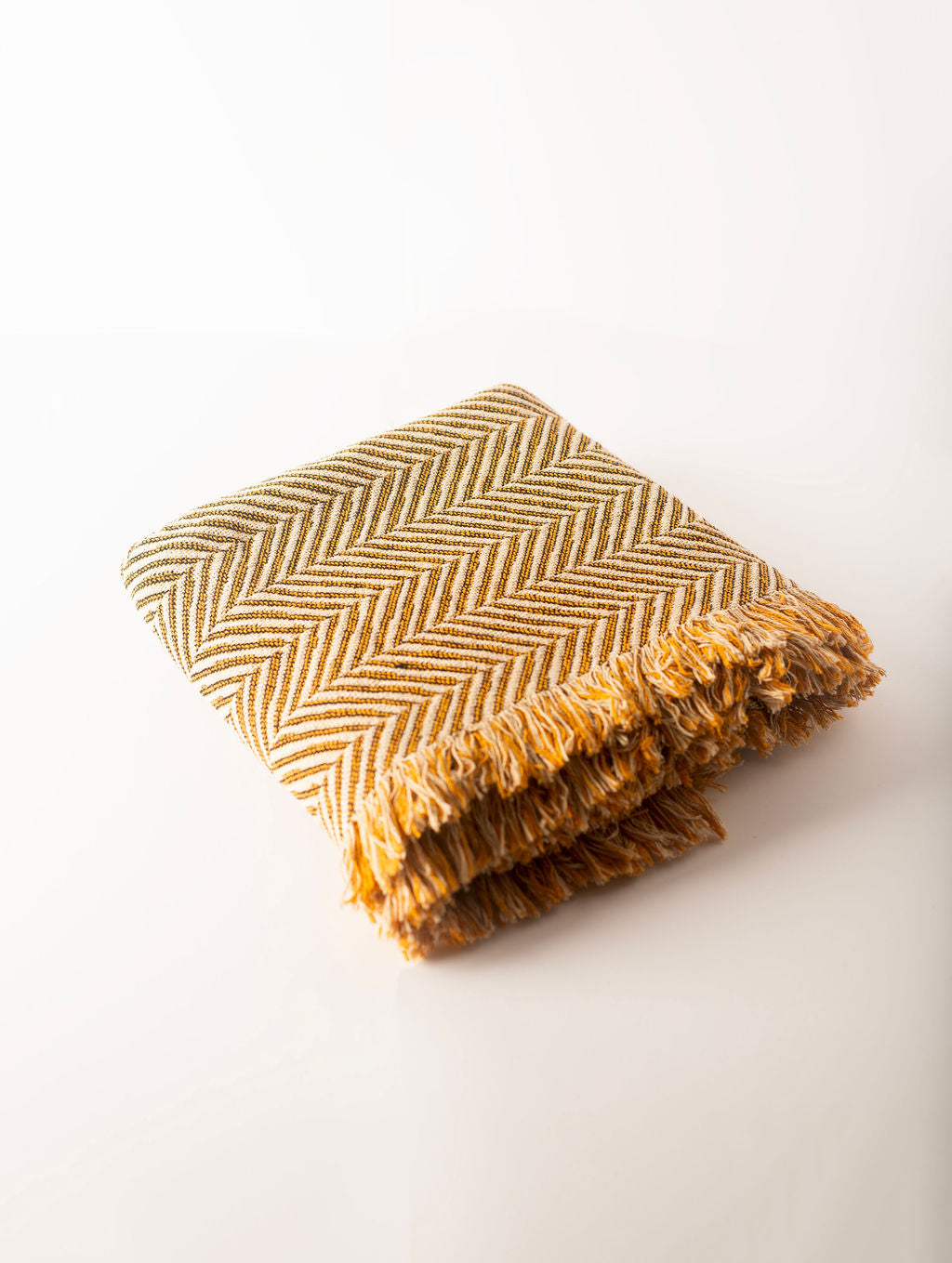 Textured blanket with chevron pattern and fringe on a white background