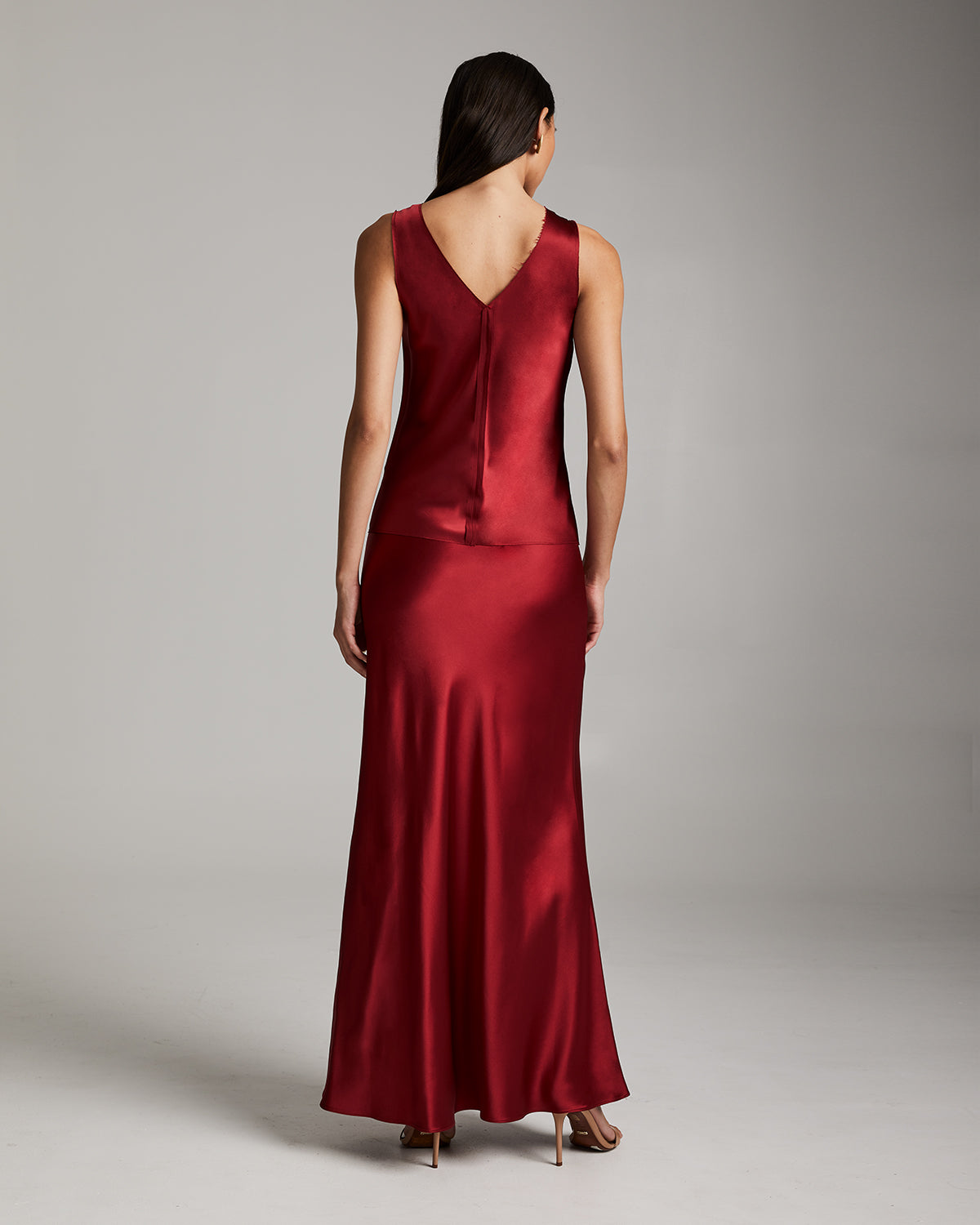 Model wearing a red silk raw edge tank top from the back