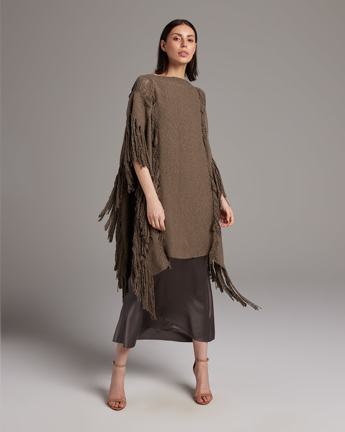 Model wearing a Lace Fringe Manta in taupe over a silk dress