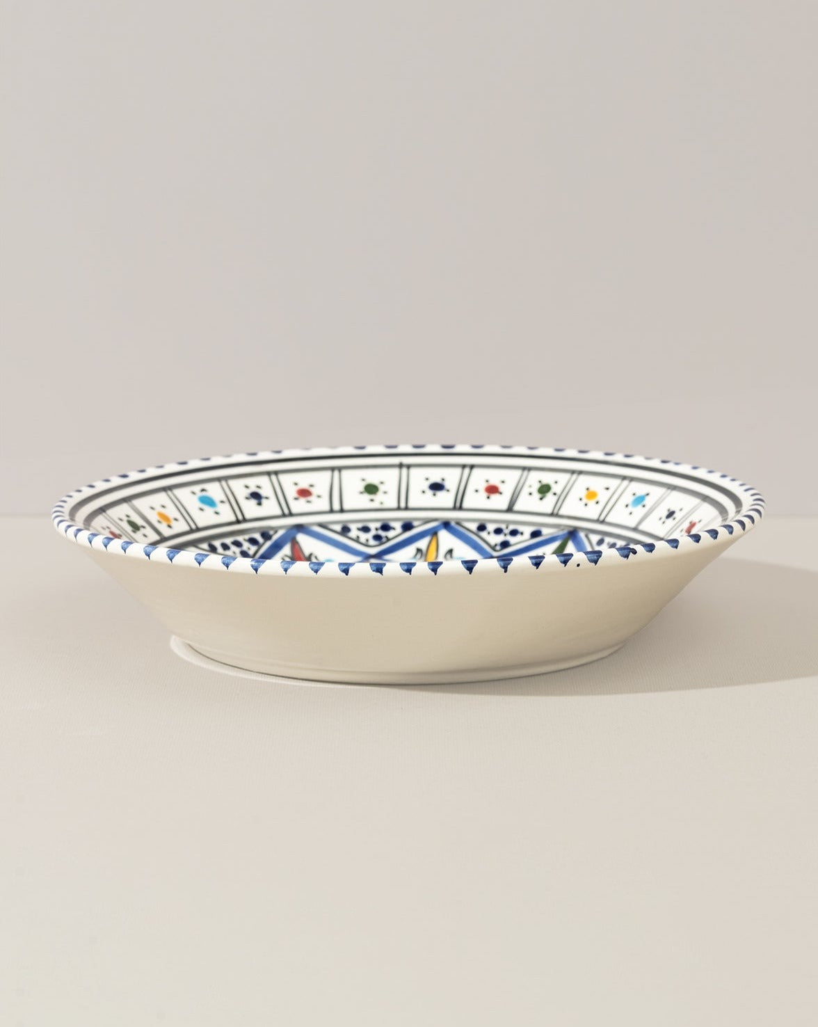 A ceramic decorative plate with a hand-painted geometric pattern predominantly in blue and white colors.