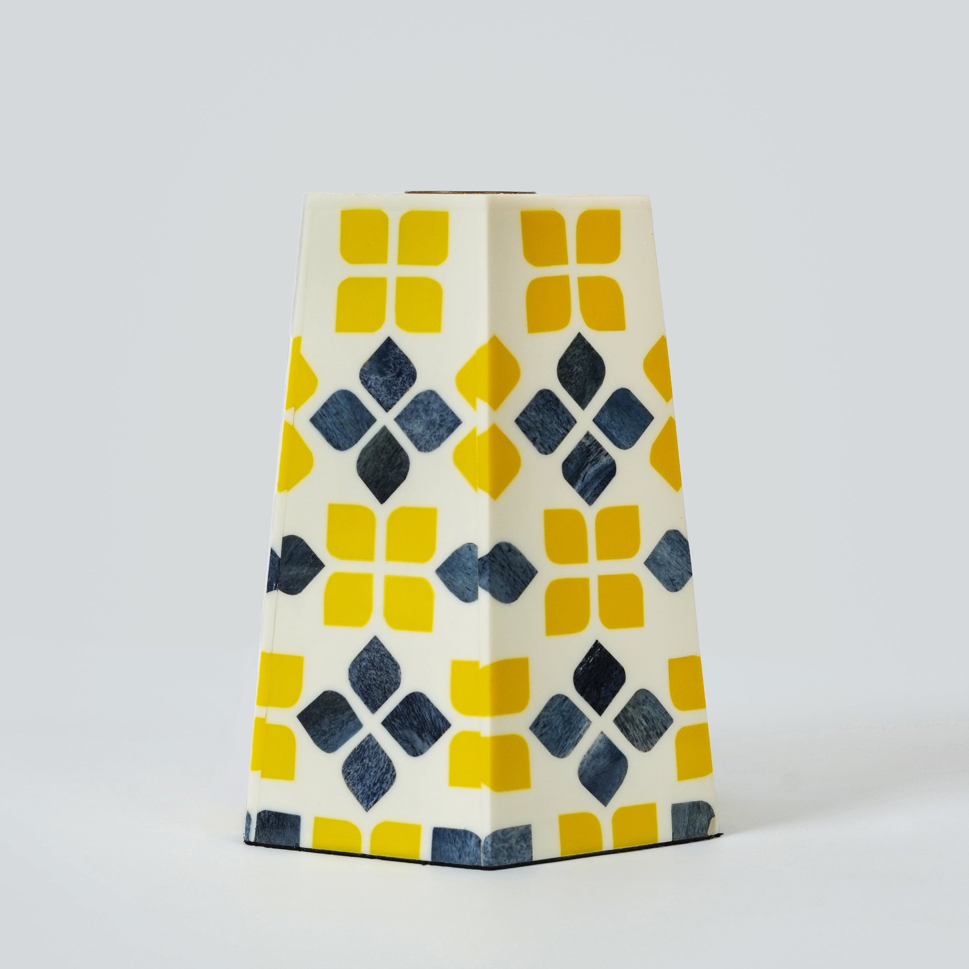 Detailed view of the hand-polished resin and bone inlay craftsmanship on a decorative yellow candle holder.

