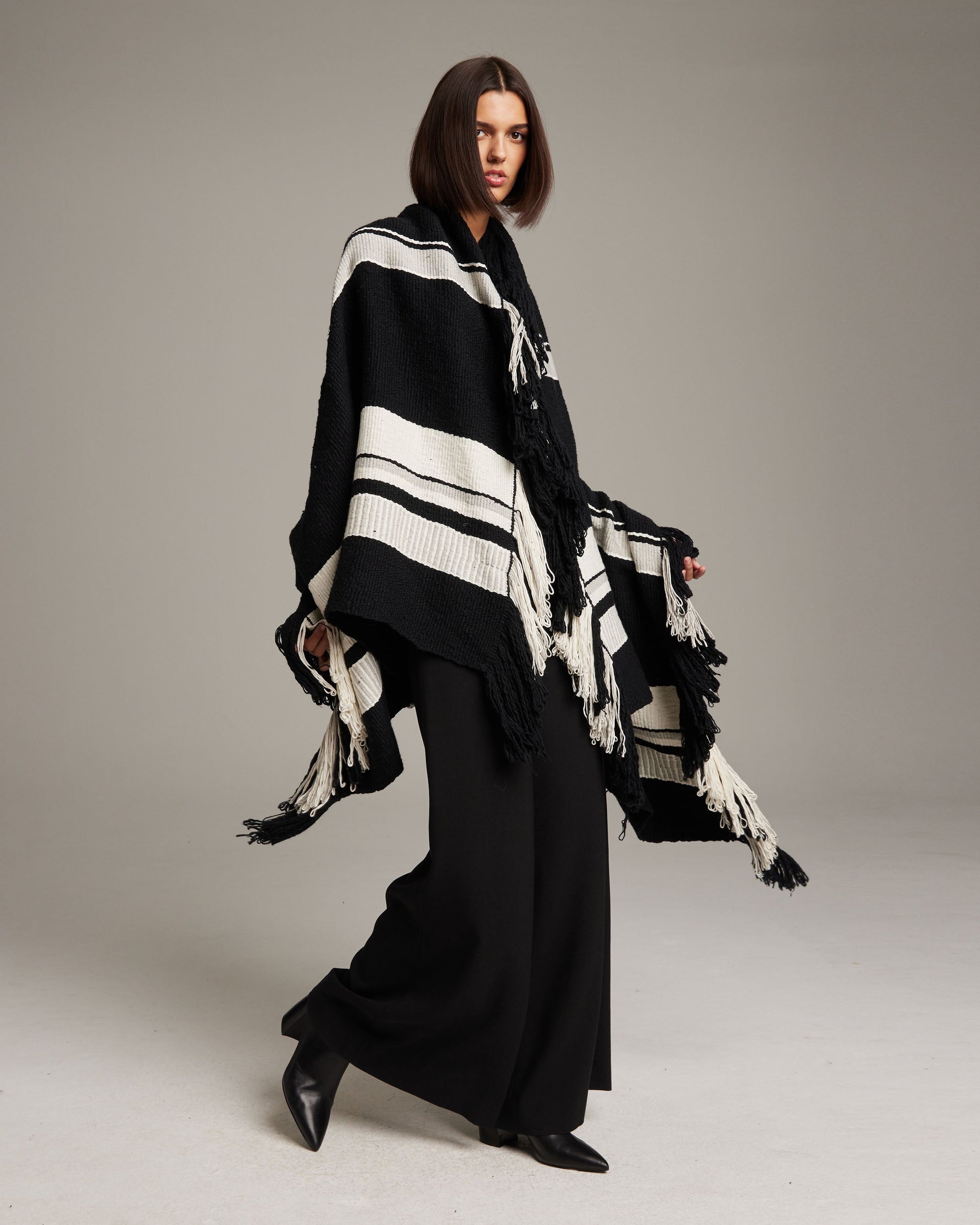 Model wearing the Granite Cascade Blanket in Pima Cotton, featuring black and white stripes and fringe.