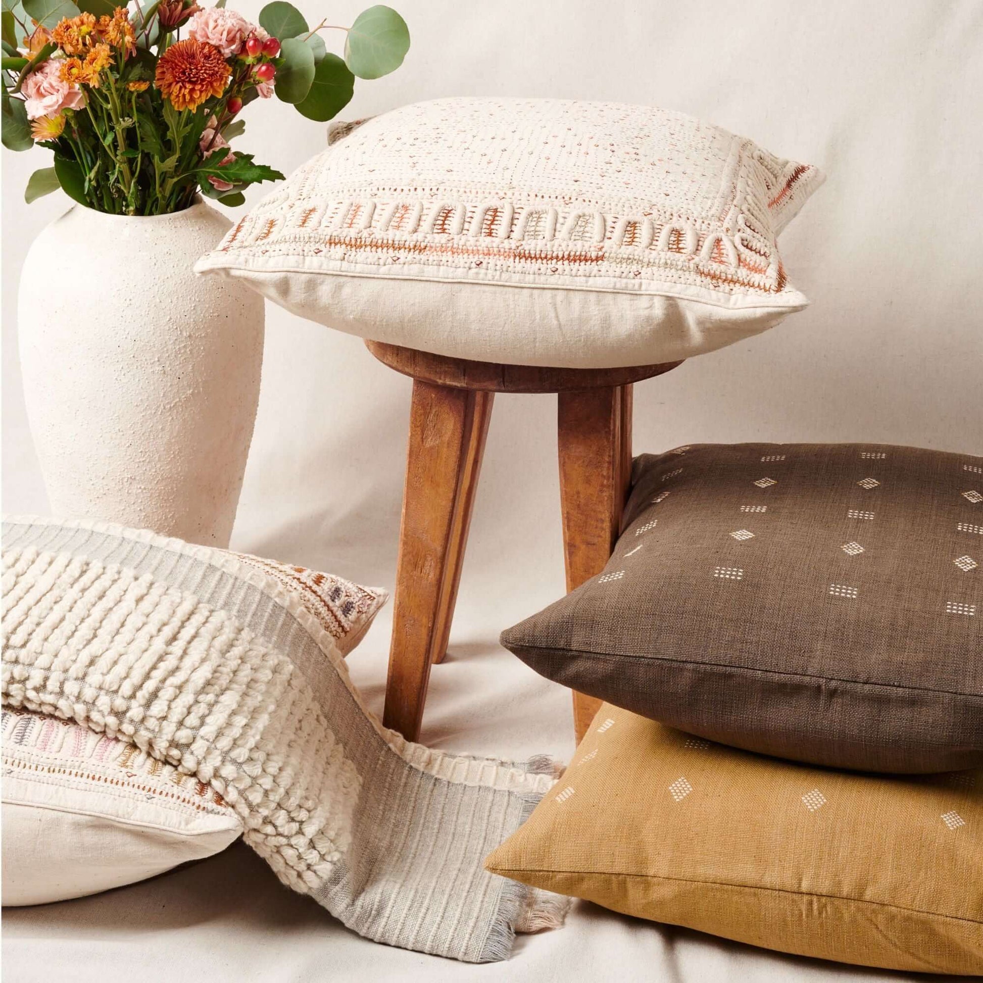 Butterscotch White Handloom Textured Plush Merino Throw displayed with decorative pillows and a vase of flowers.