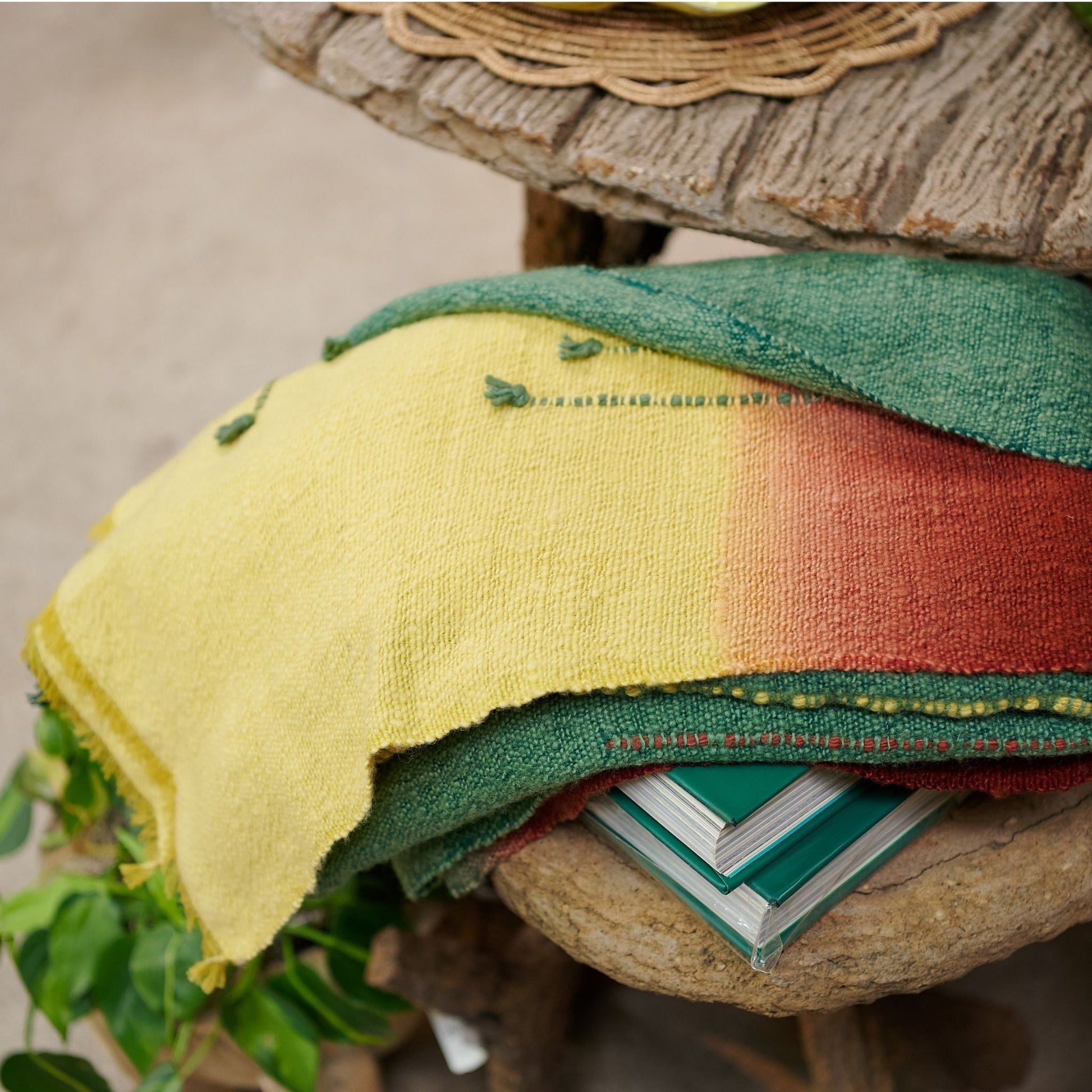 Avocado Green Multi Color Warm Hues Hand Woven Hand Knotted Textured Merino Throw displayed on a wooden table.
