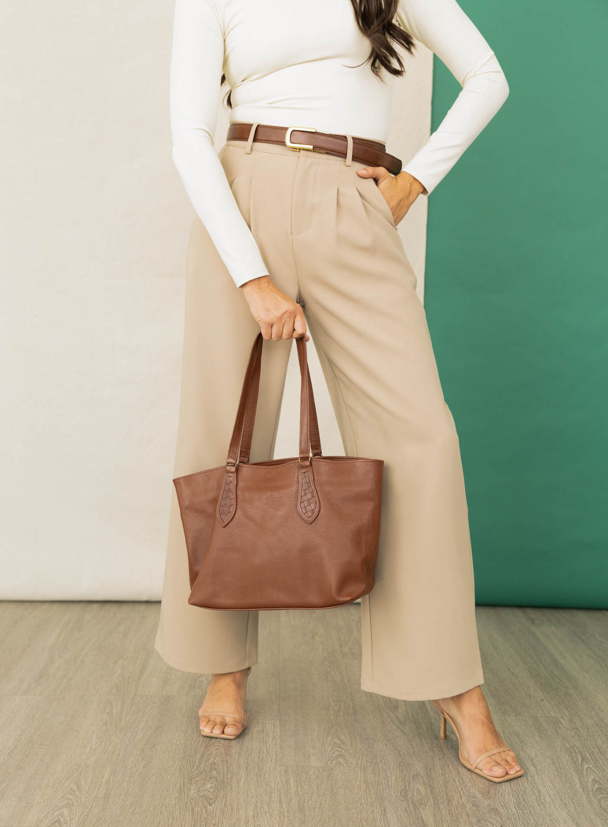 The mid tote in mahogany from the spring collection held by model standing up.