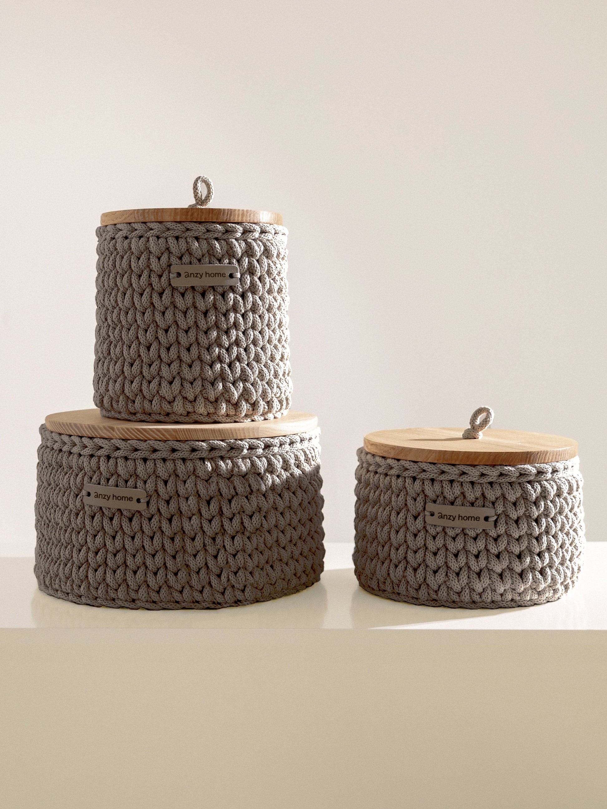Three woven baskets with wooden lids on a light background