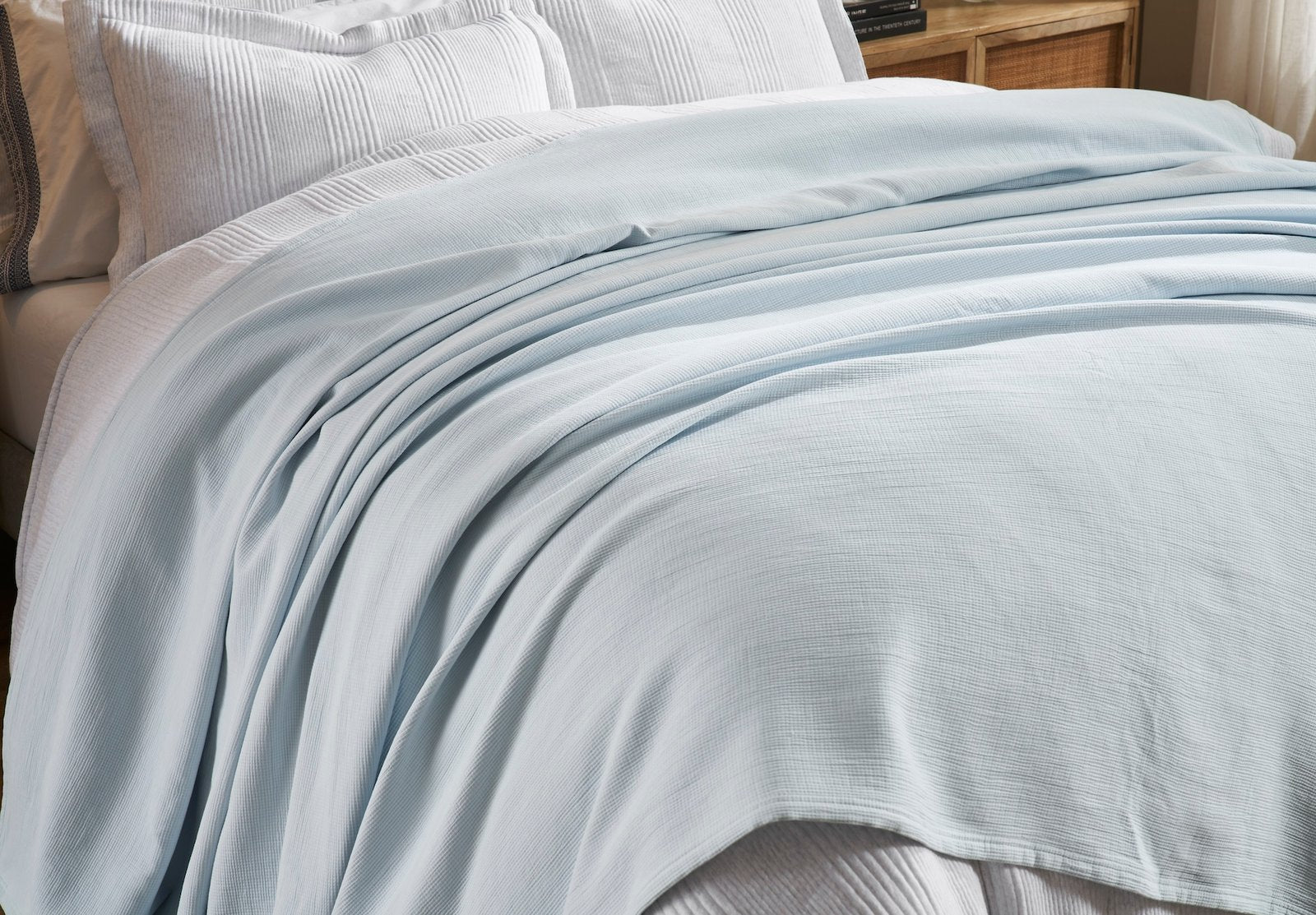 BL-859-9496_3|Close-up of a light blue waffle weave blanket draped over a bed. Highlights soft texture and comfortable design.