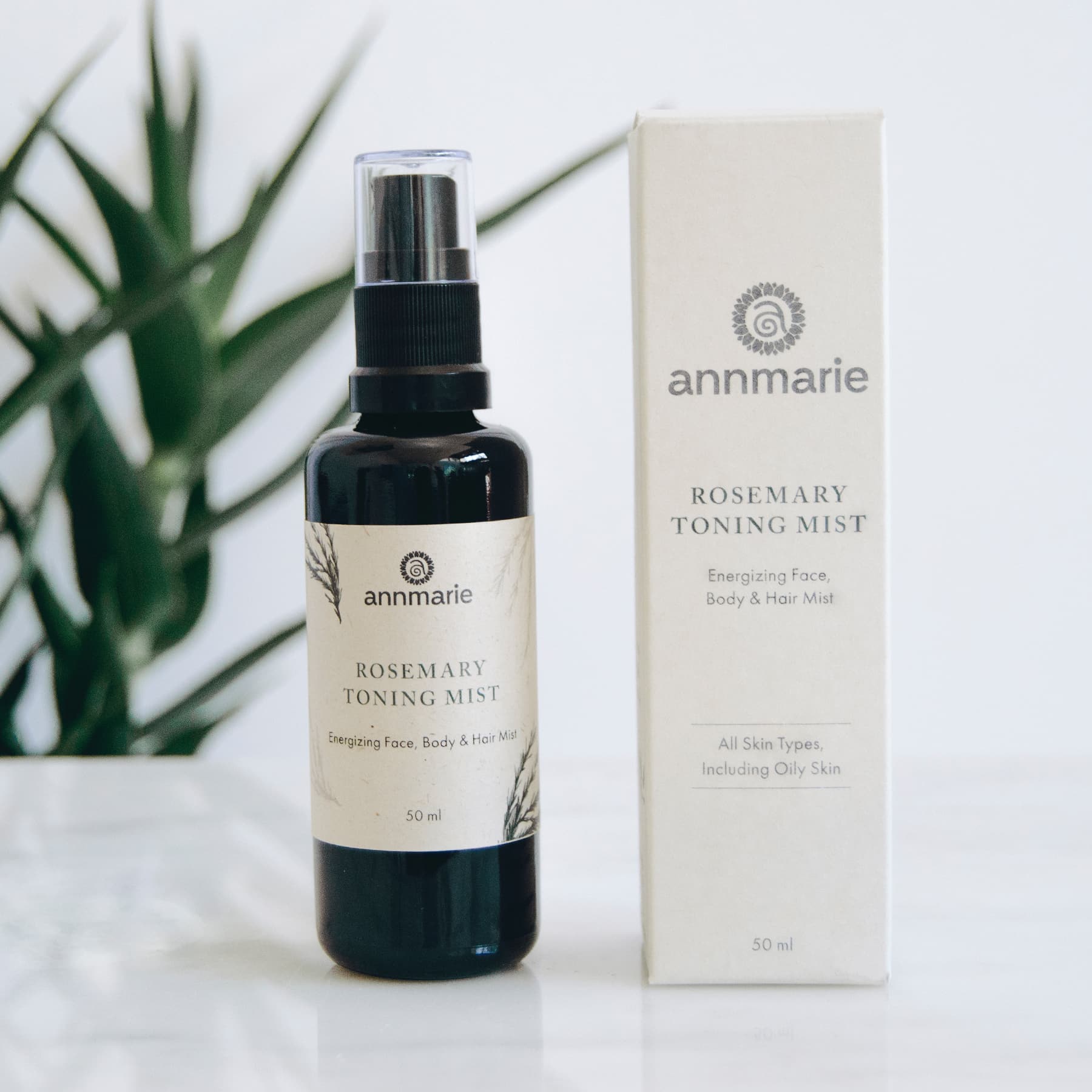 Annmarie Rosemary Toning Mist bottle and packaging on a white surface with a plant in the background