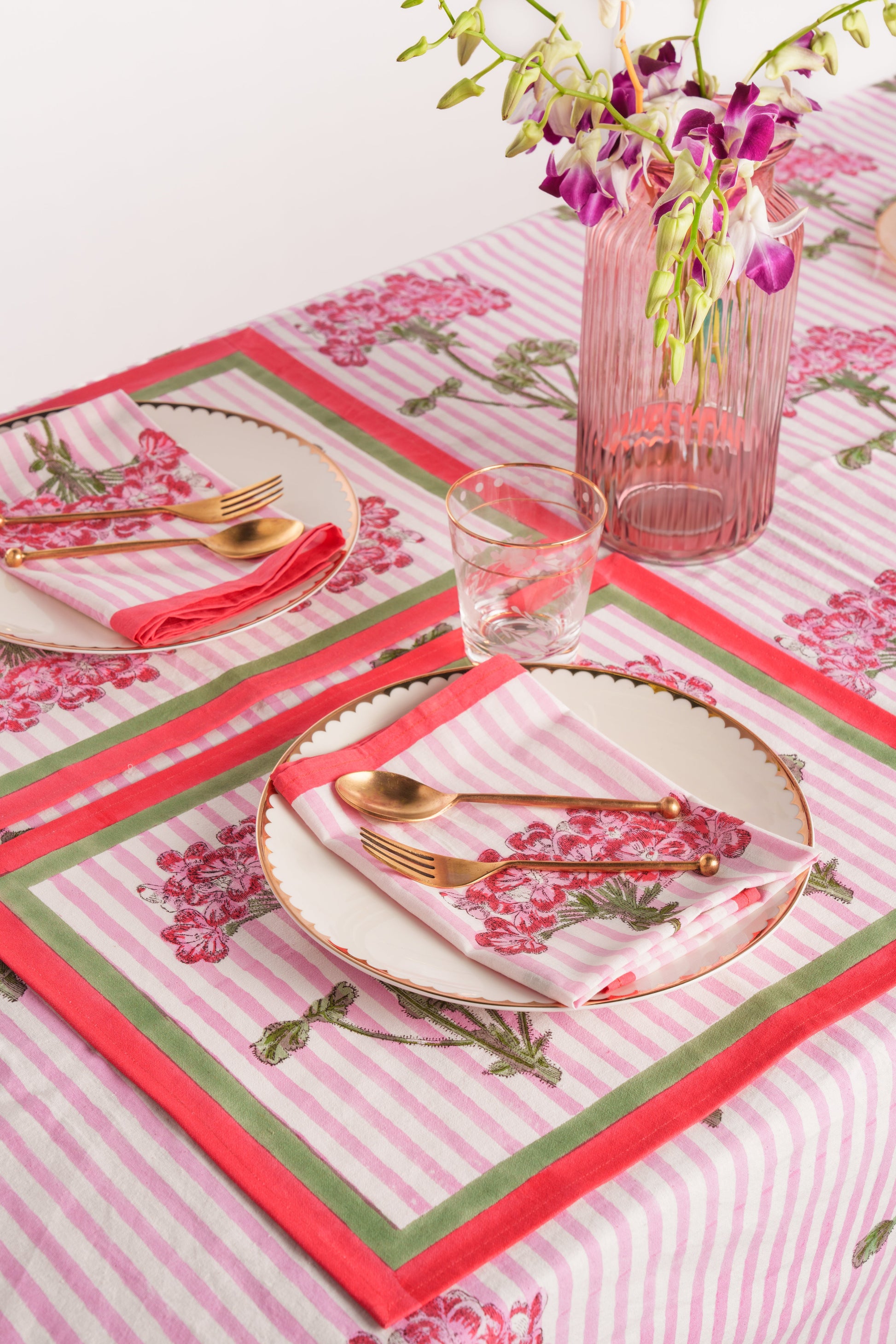 Pink hydrangea blockprint tablecloth with pink stripes, gold plates, matching napkins