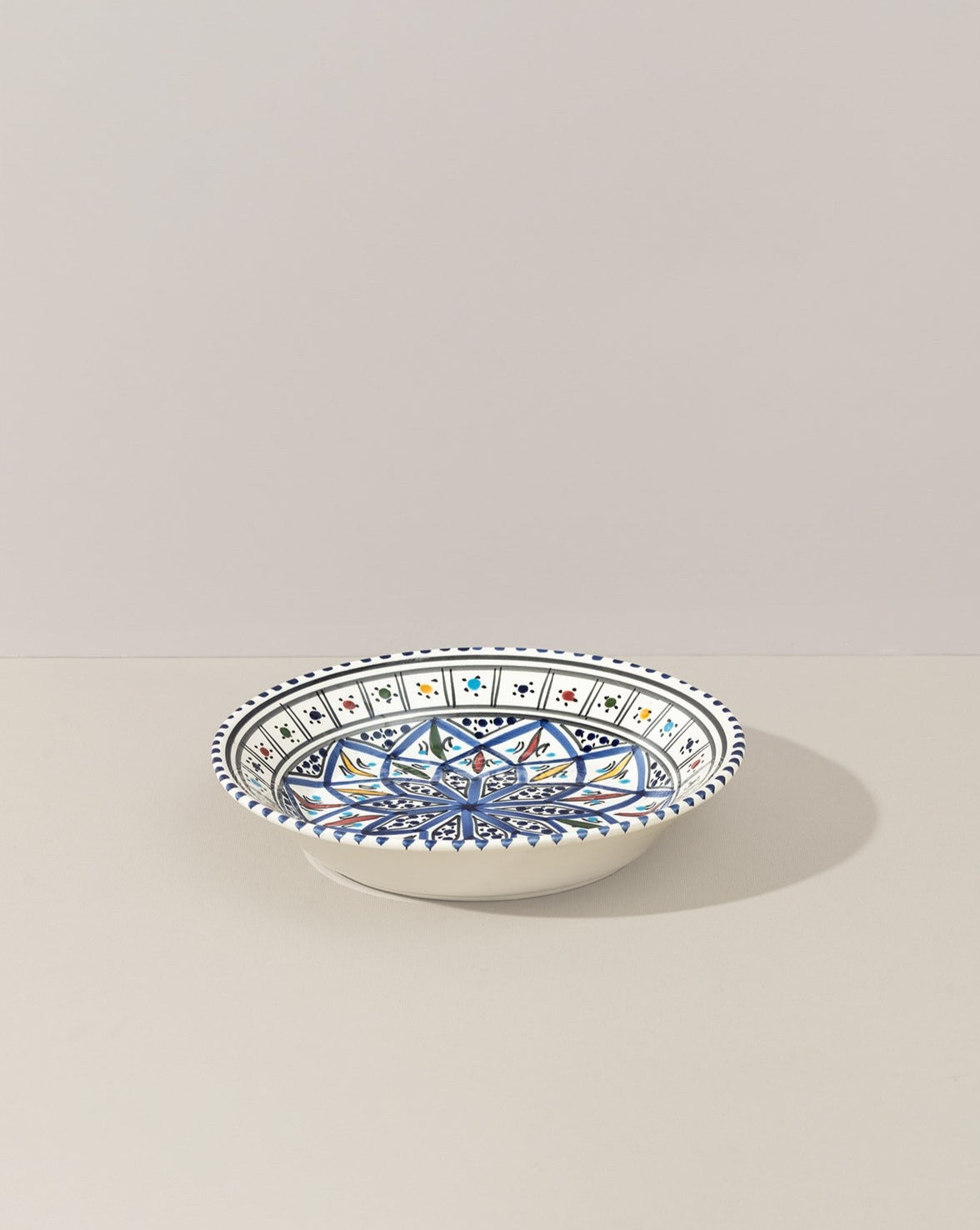 A ceramic decorative plate with a hand-painted geometric pattern predominantly in blue and white colors.