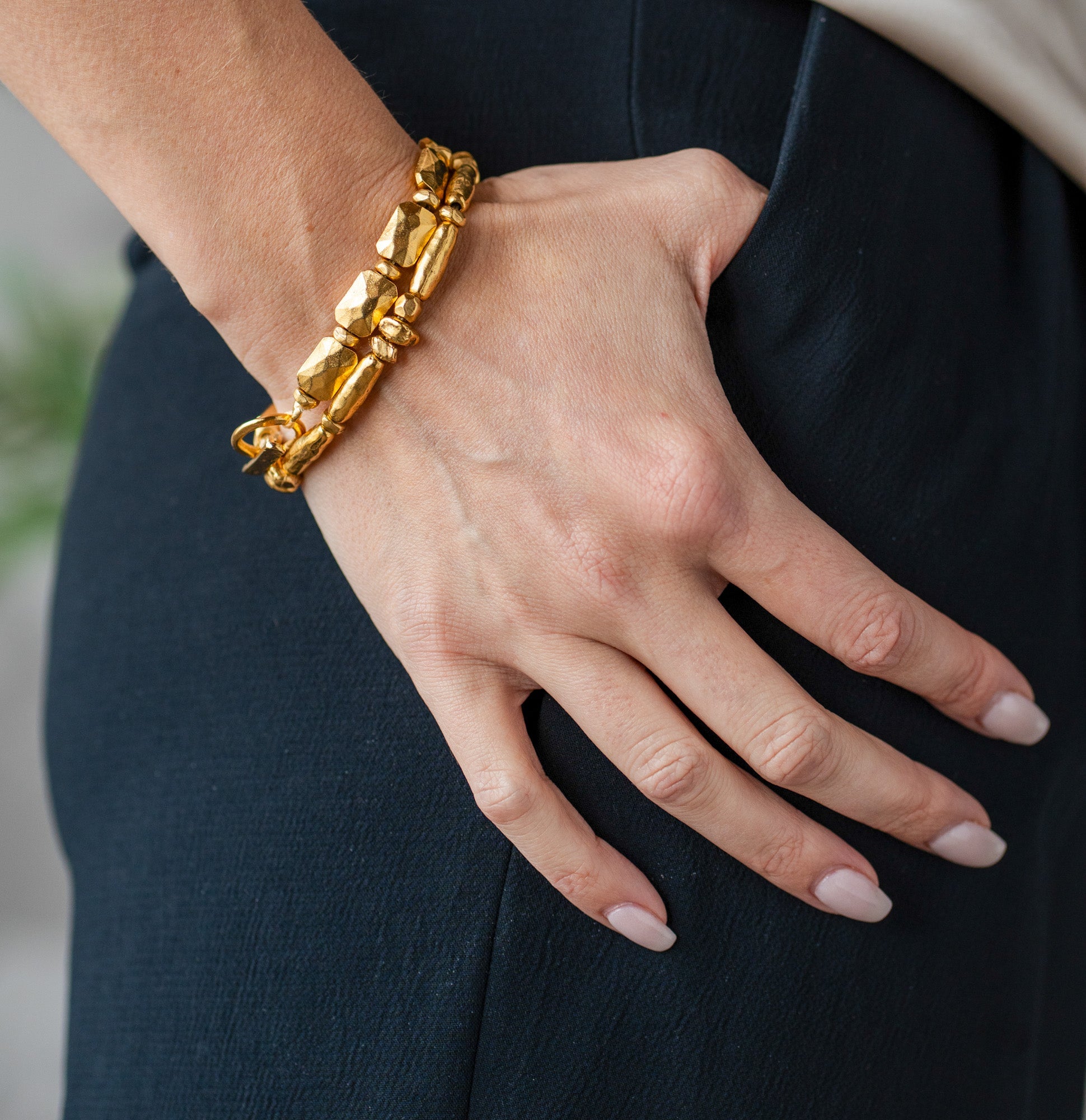 Gold-toned bracelet with sculptural organic beads and a toggle clasp, styled in a circular shape.