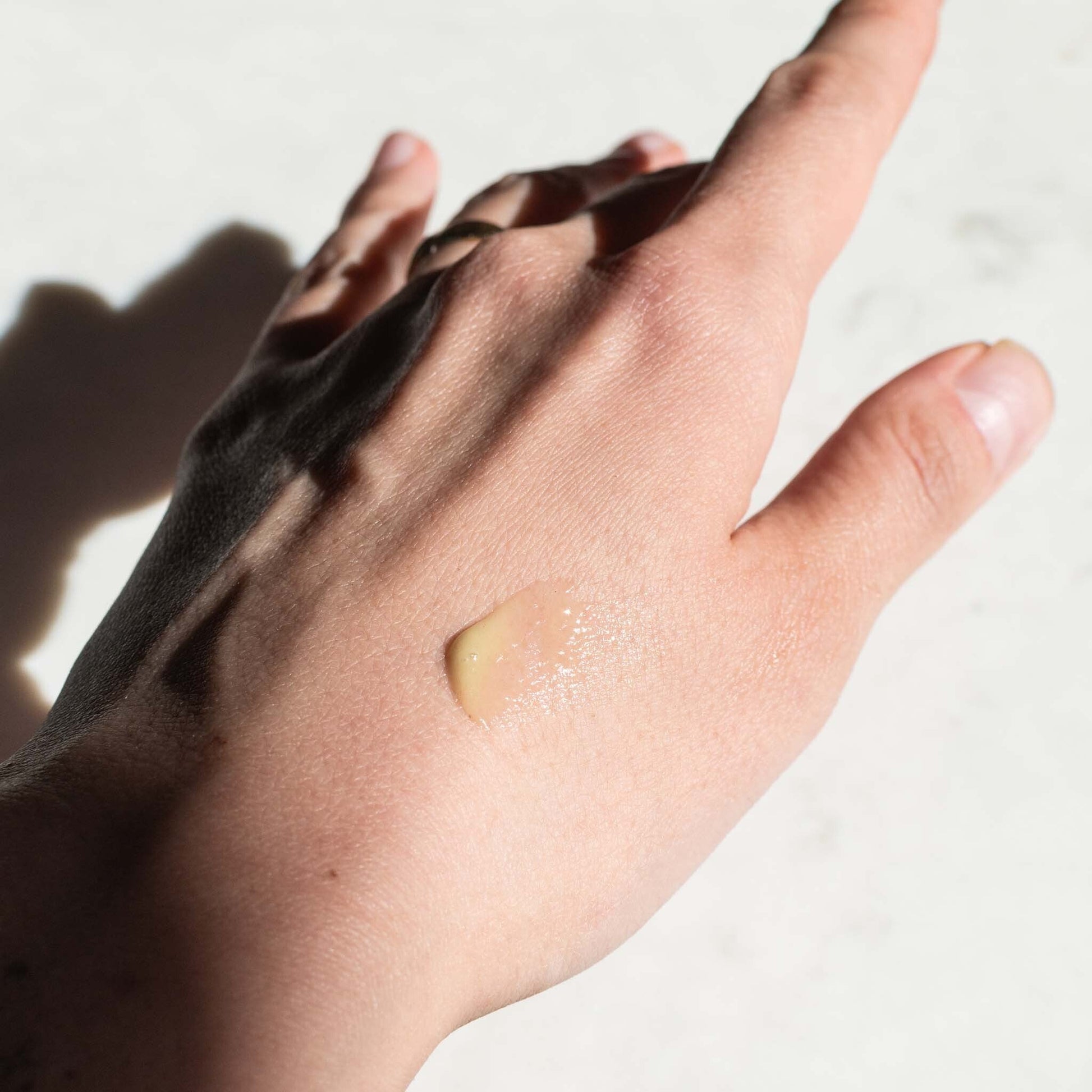 Close-up of a small drop of Activated Hemp Serum on the back of a hand showing the texture and consistency of the skincare product.