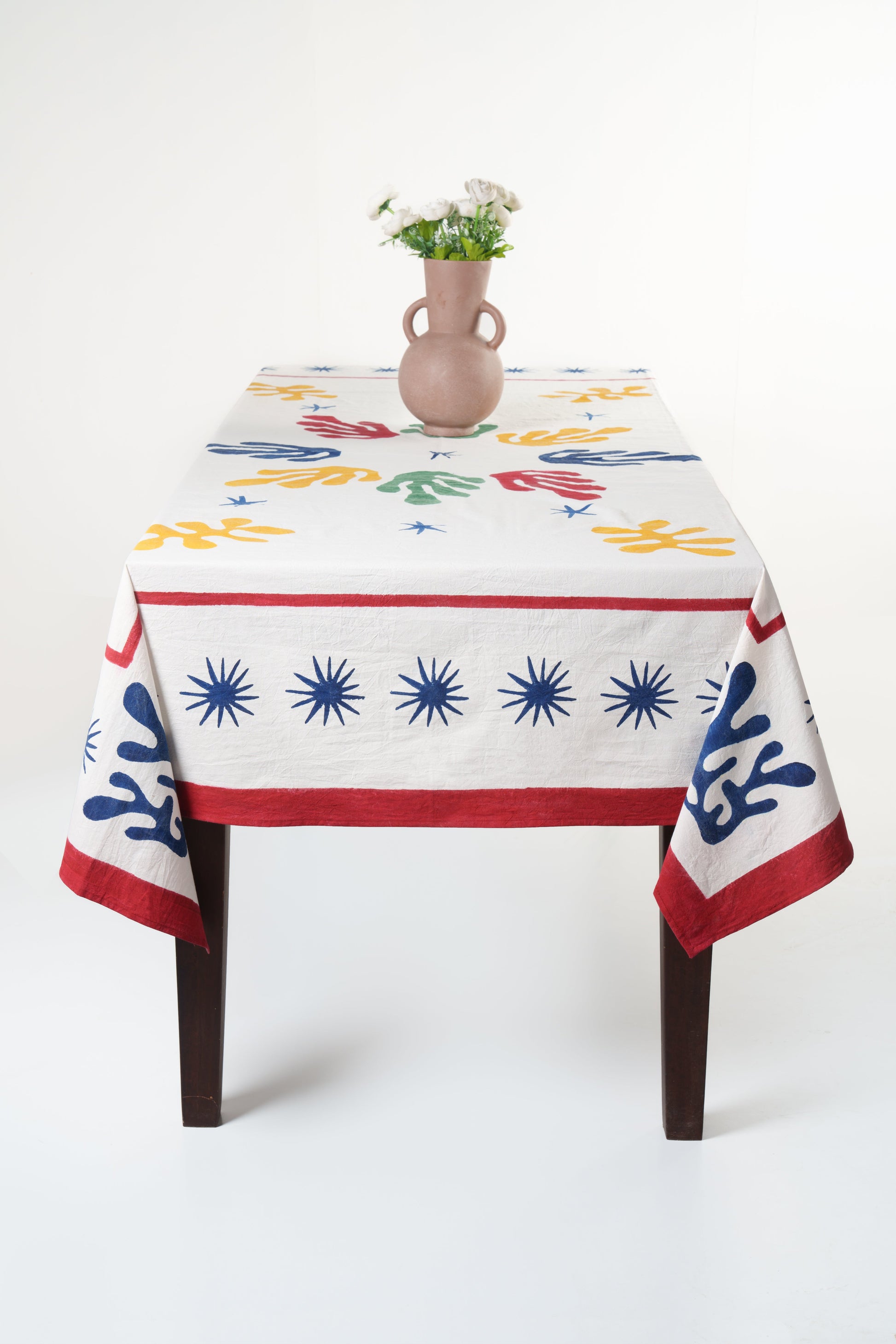 Celestial Matisse blockprint tablecloth on wooden table with pink vase