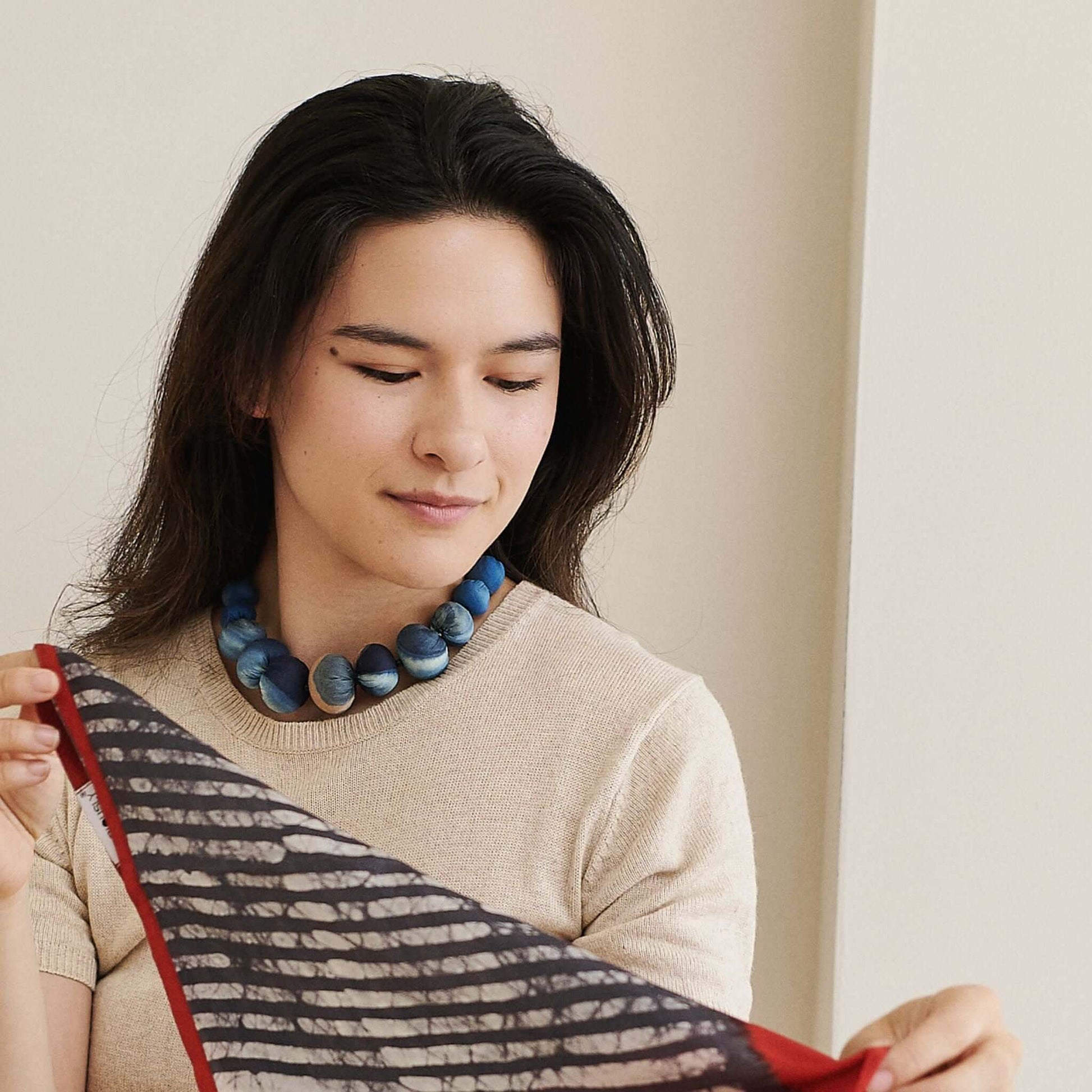 Mihika silk beaded necklace worn by a woman holding a patterned scarf, showcasing modern artisanal design.