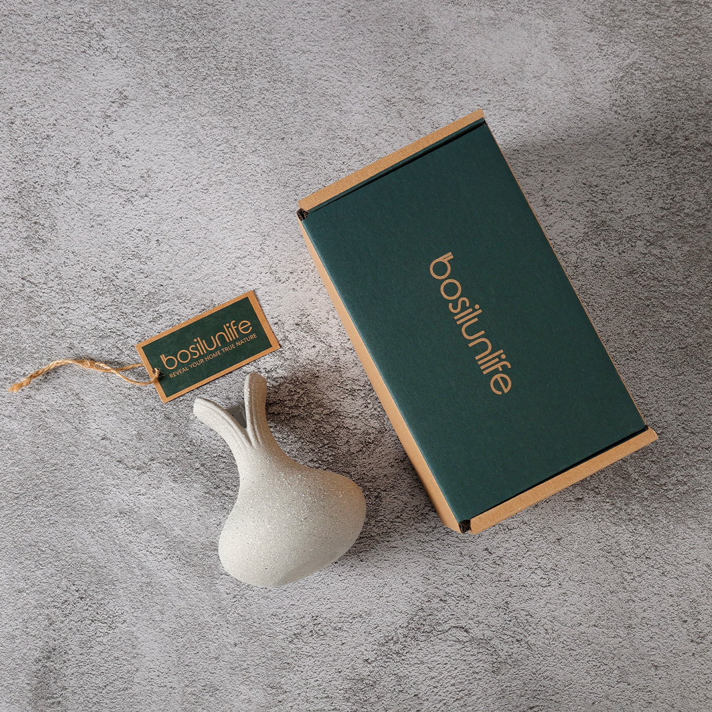 Green box with 'bosilunife' branding, small white ceramic item, and matching tag on a gray surface