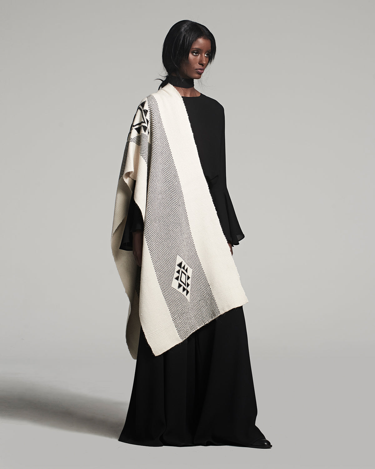 Model wearing the Estrella Shawl, featuring geometric patterns in black and cream.