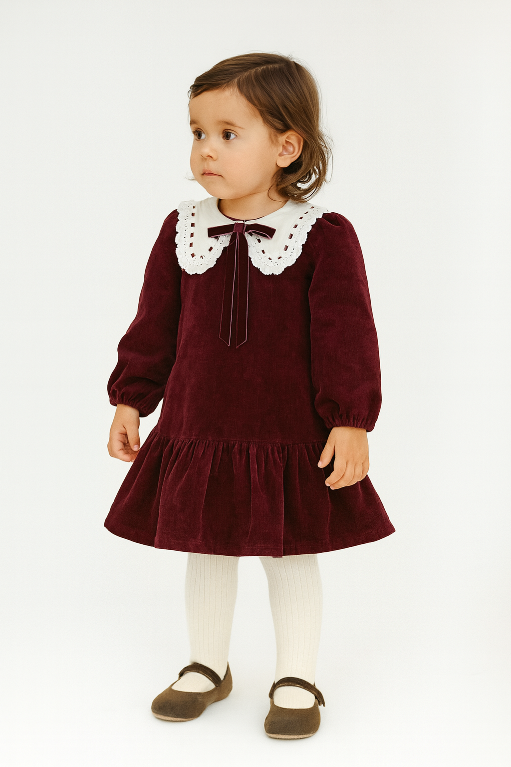 Young girl wearing a burgundy dress with a white collar on a white background