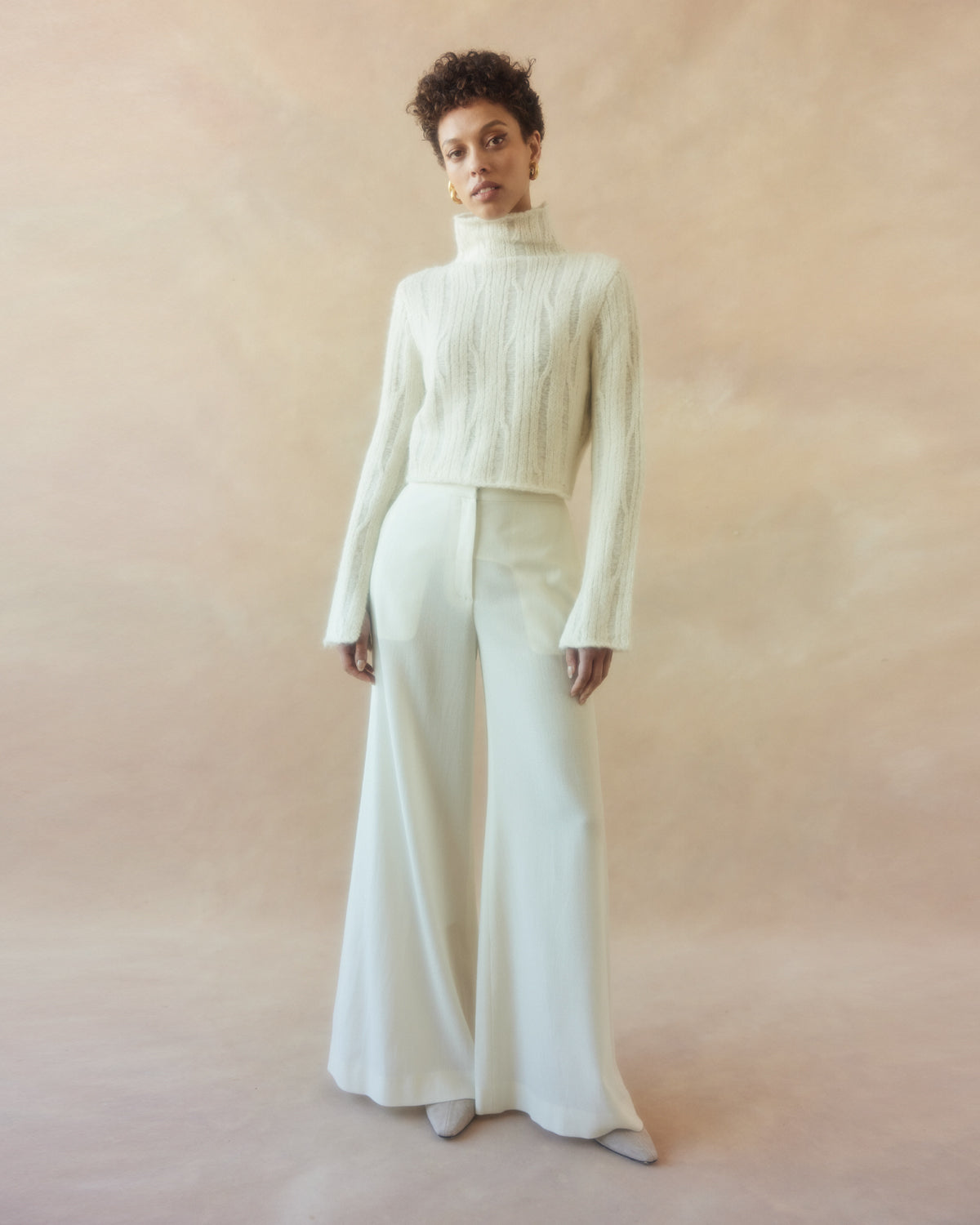 Model wearing a ribbed cropped sweater with wide-leg trousers against a soft background
