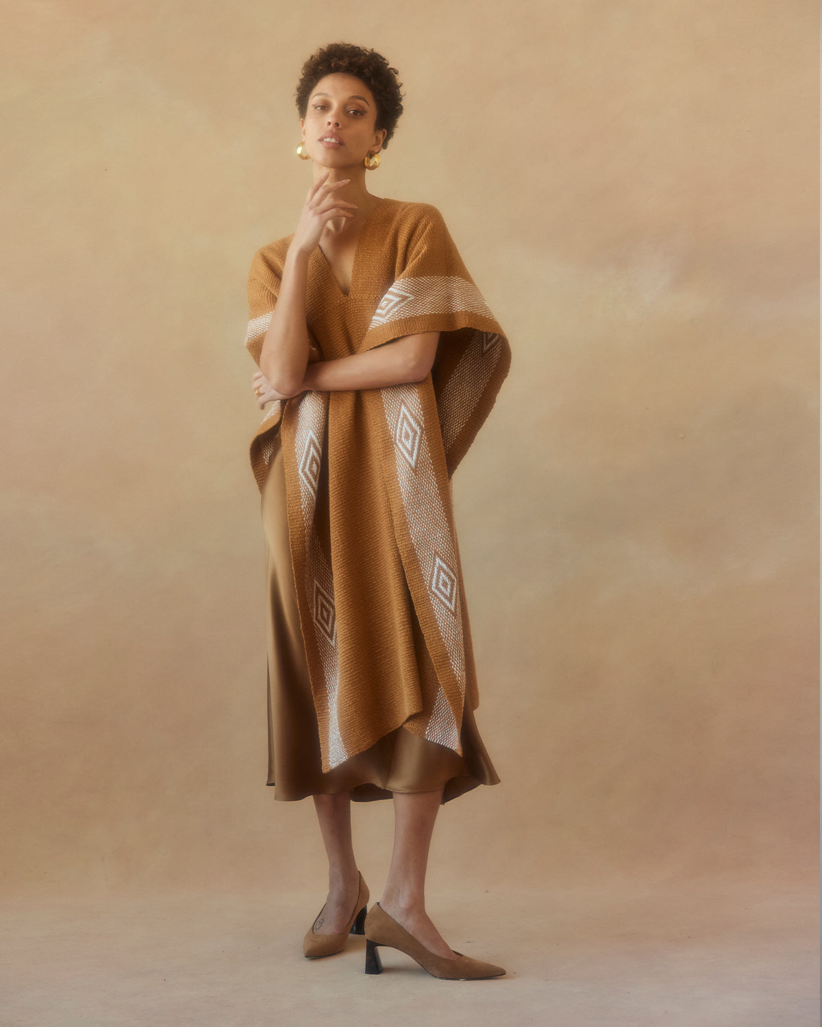 Model wearing a hand-loomed Manta Diamante in gold and ivory with diamond patterns