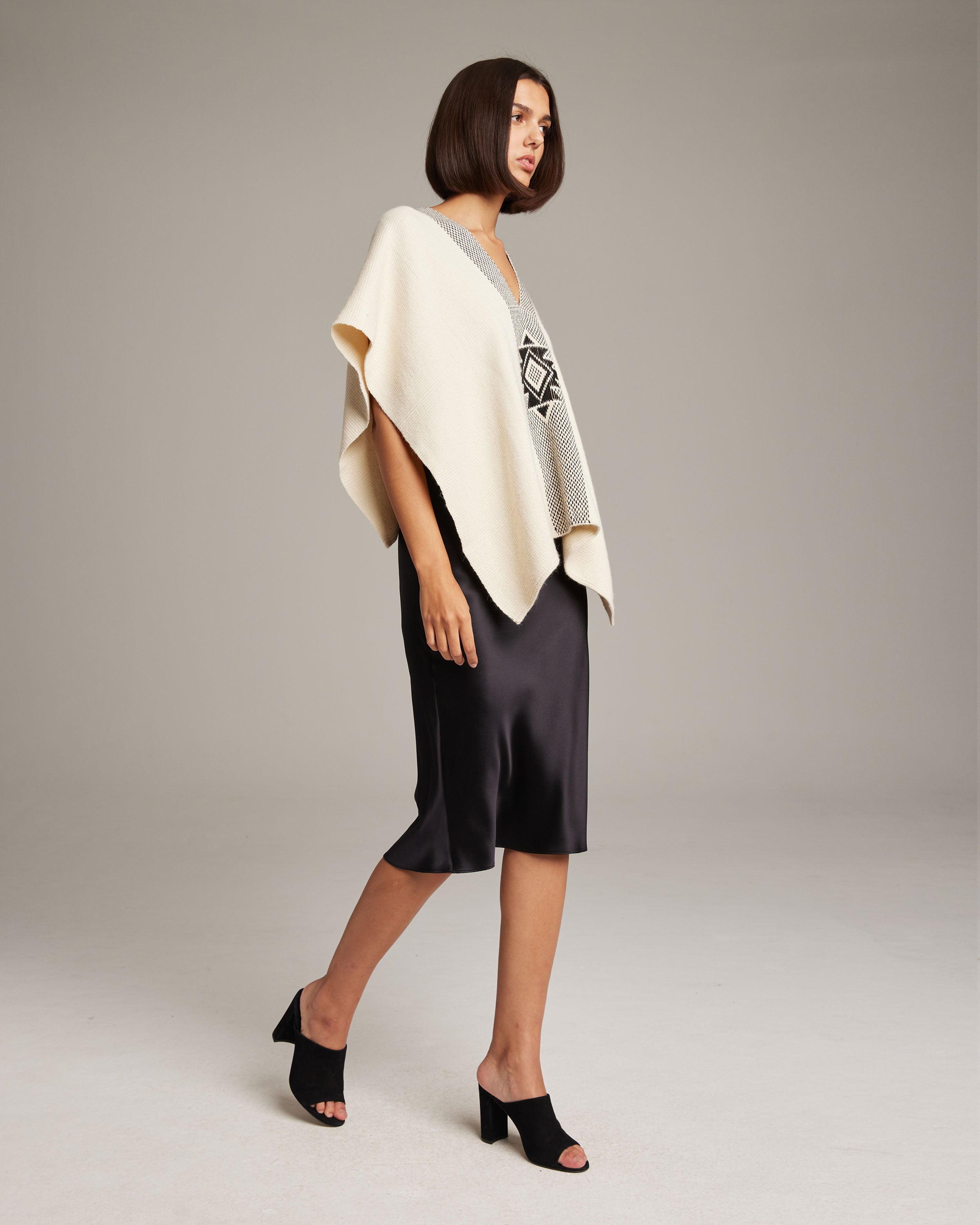 Model wearing the Manta Estrella poncho in ivory with a geometric pattern