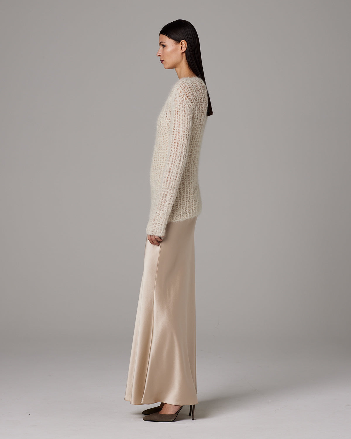 Model wearing Open Mesh Boatneck Sweater in ivory, paired with a satin skirt.