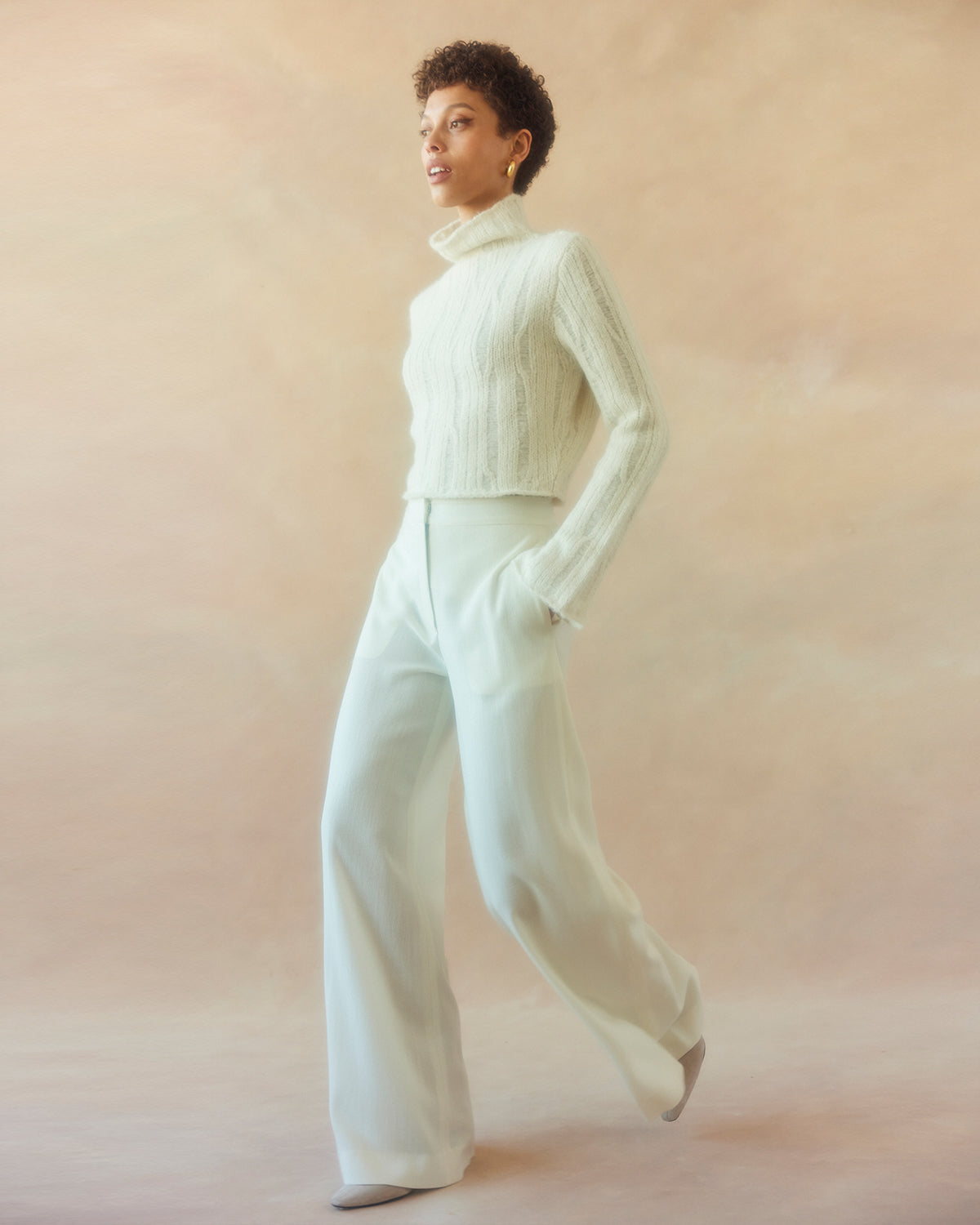 Model wearing an ivory ribbed cropped sweater with wide-leg trousers