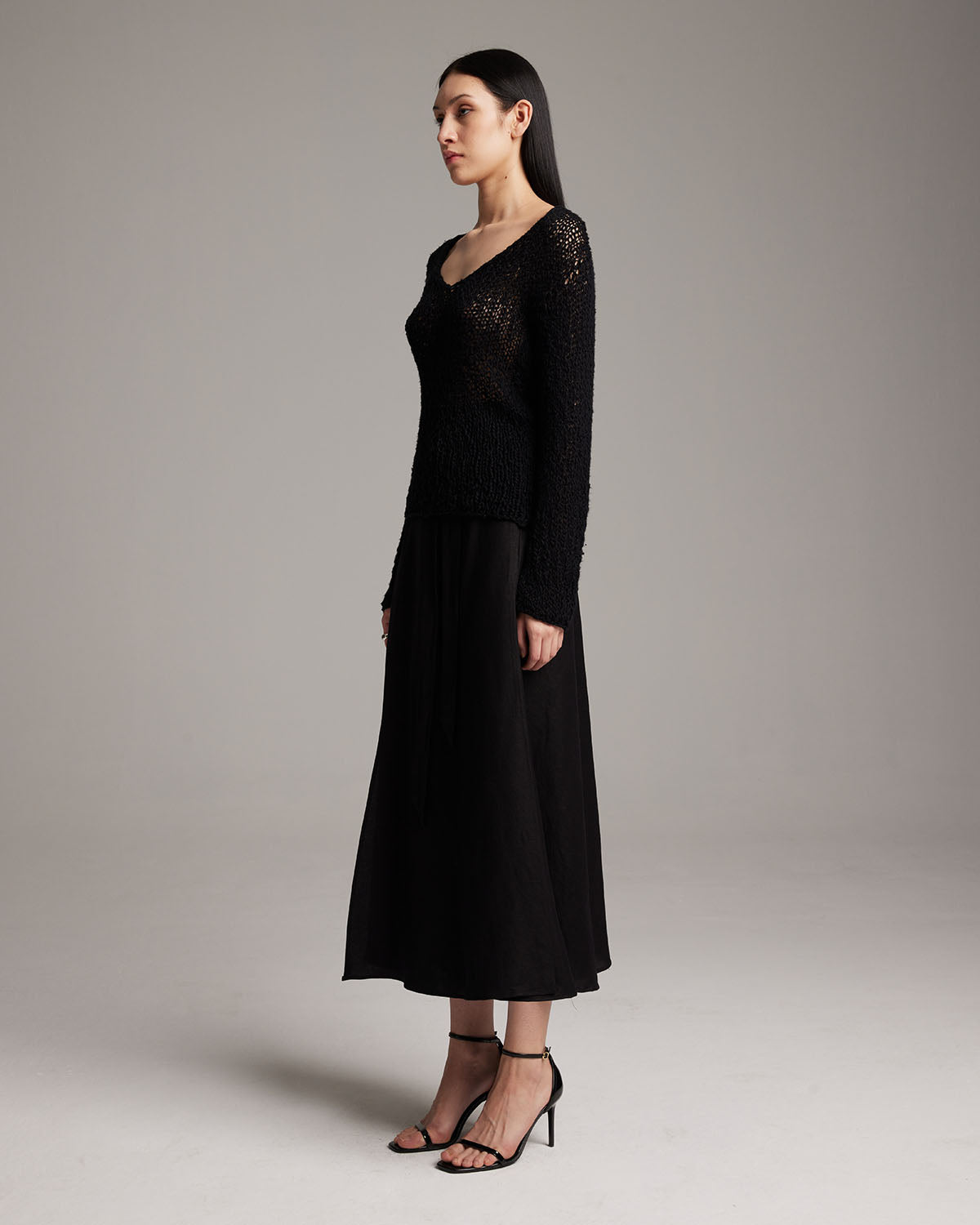 Model wearing a black Flammé Loose Knit Long Sweater with a long black skirt