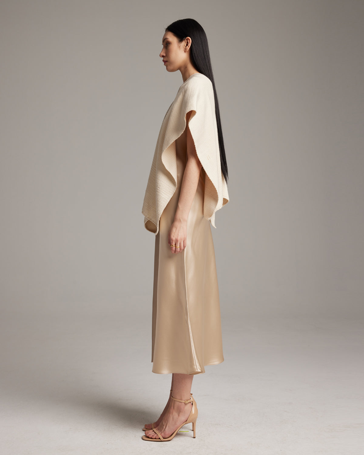 Model wearing a handwoven ivory poncho made of Pima cotton, side view.