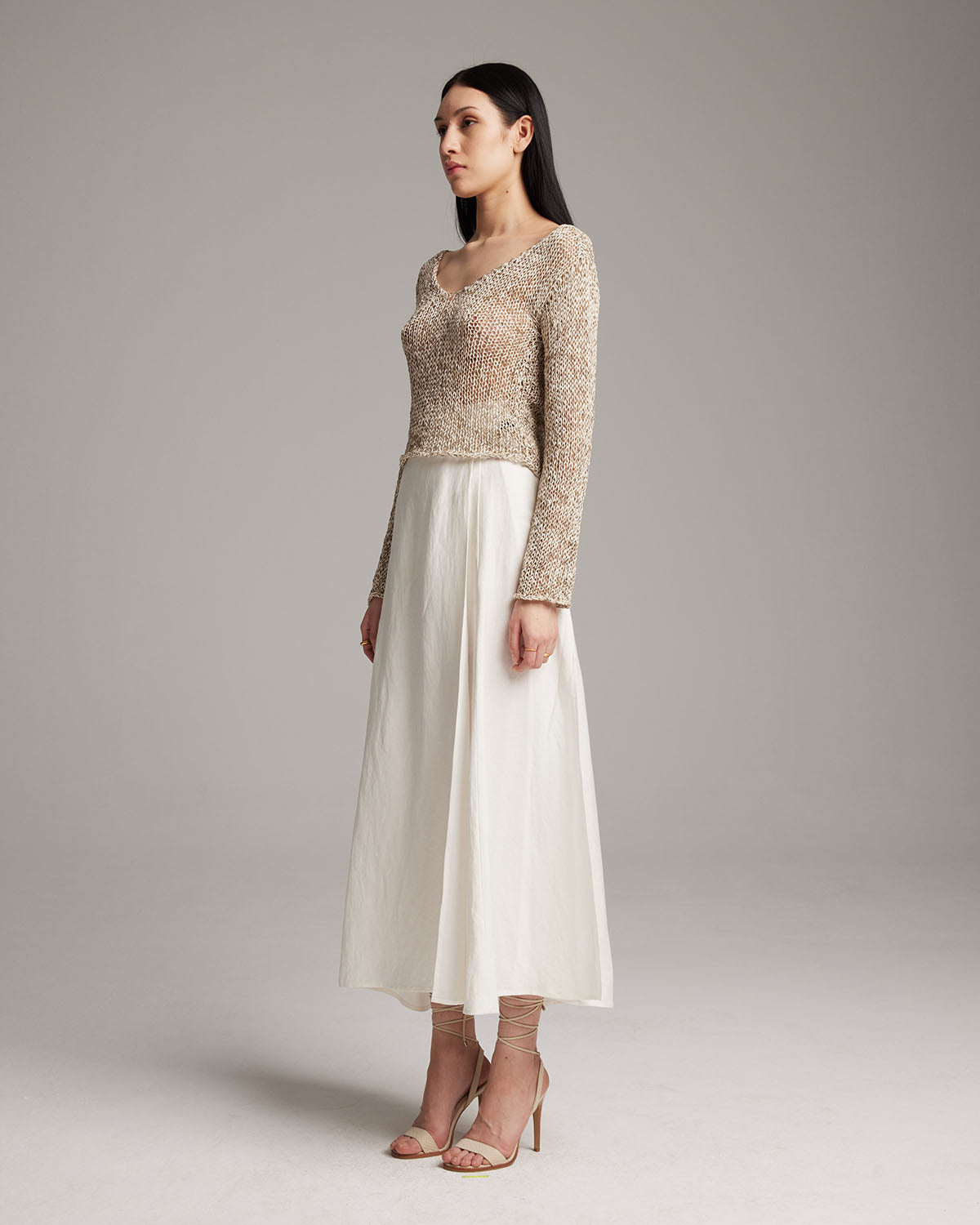 Model wearing a VOZ Cropped Loose Knit Sweater with a long white skirt