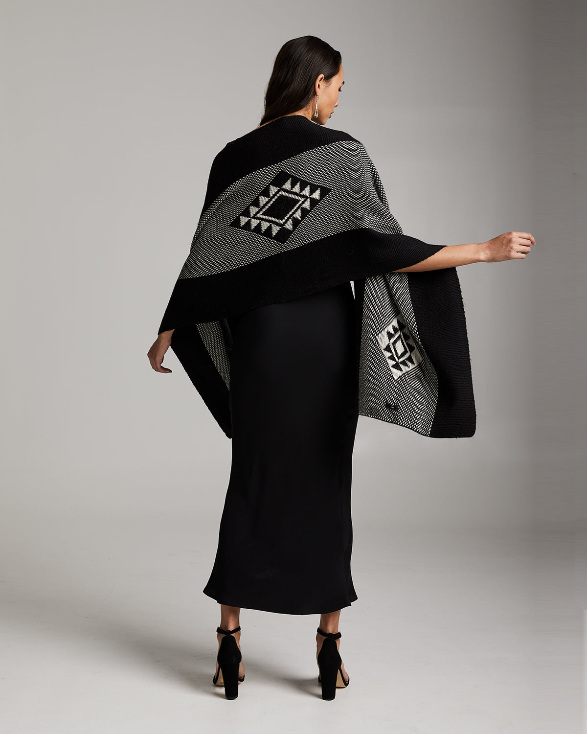 Model wearing a black and grey Estrella Shawl with geometric patterns, showcasing the back view.