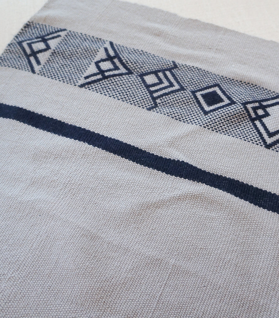 Close-up of a handwoven textile featuring geometric patterns in navy and beige.