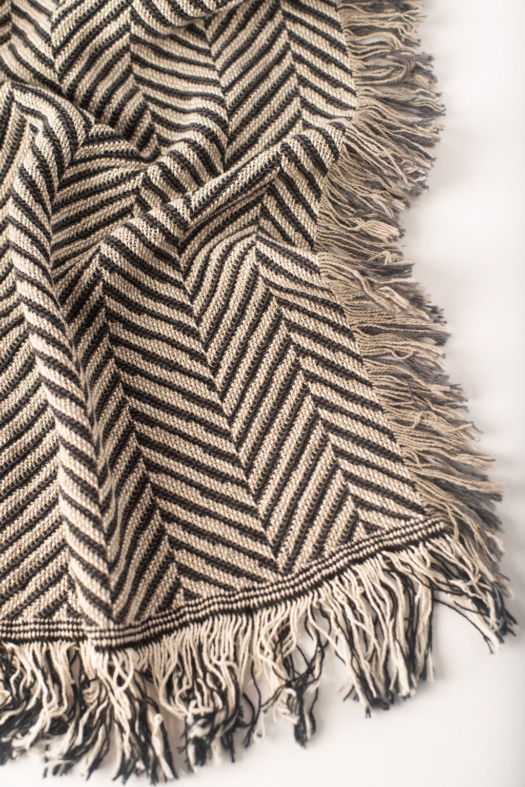 Close-up of Henry Stone charcoal gray and cream herringbone woven cotton throw with fringe