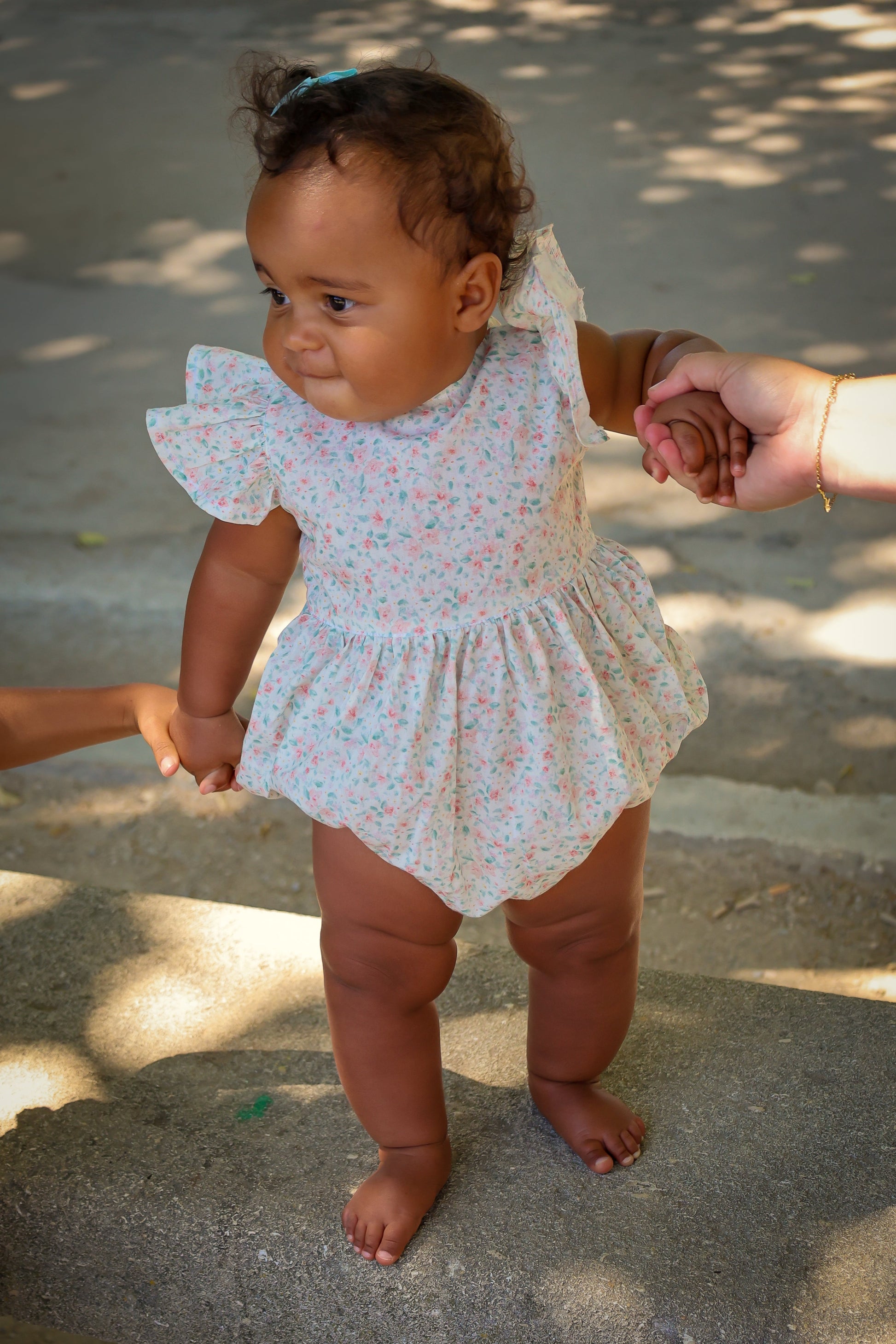 Baby in a floral Josie bubble being held by an adult outdoors
