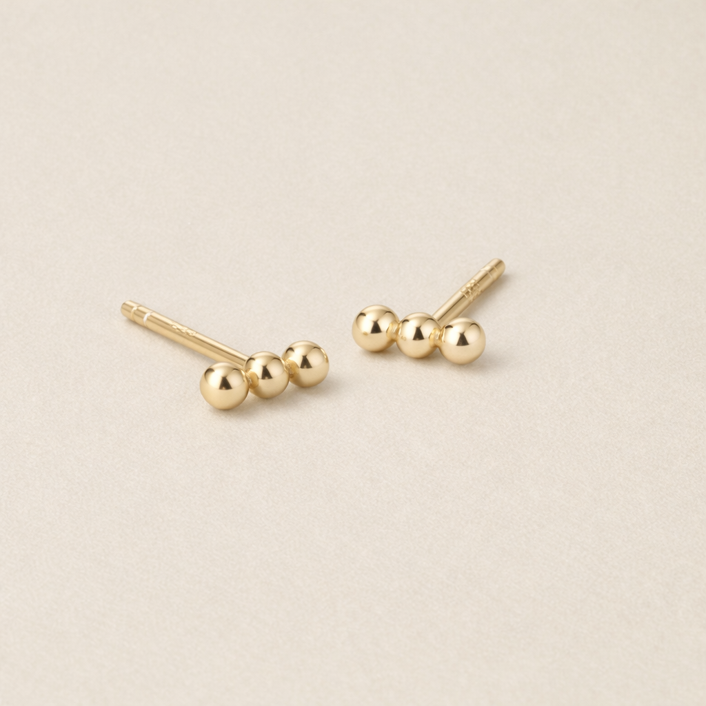 Pair of gold stud earrings on a beige background
