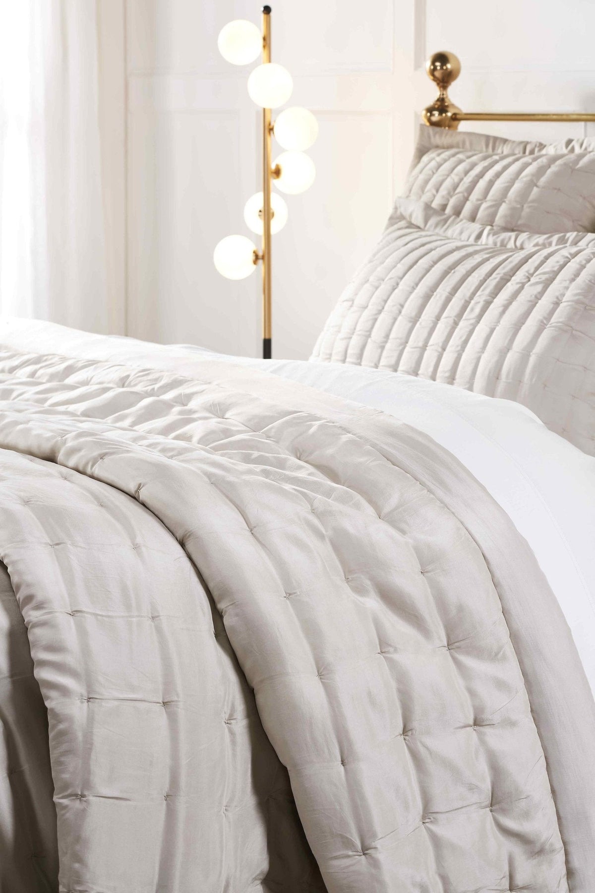 QT-334-9496_3|Elegant light beige quilted quilt draped on a bed with matching pillow shams, enhancing a serene bedroom style.