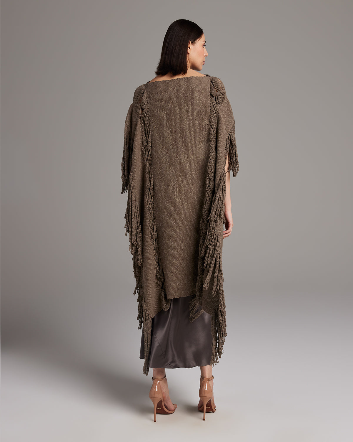 Model wearing a brown Lace Fringe Manta with fringe details, styled over a satin dress.