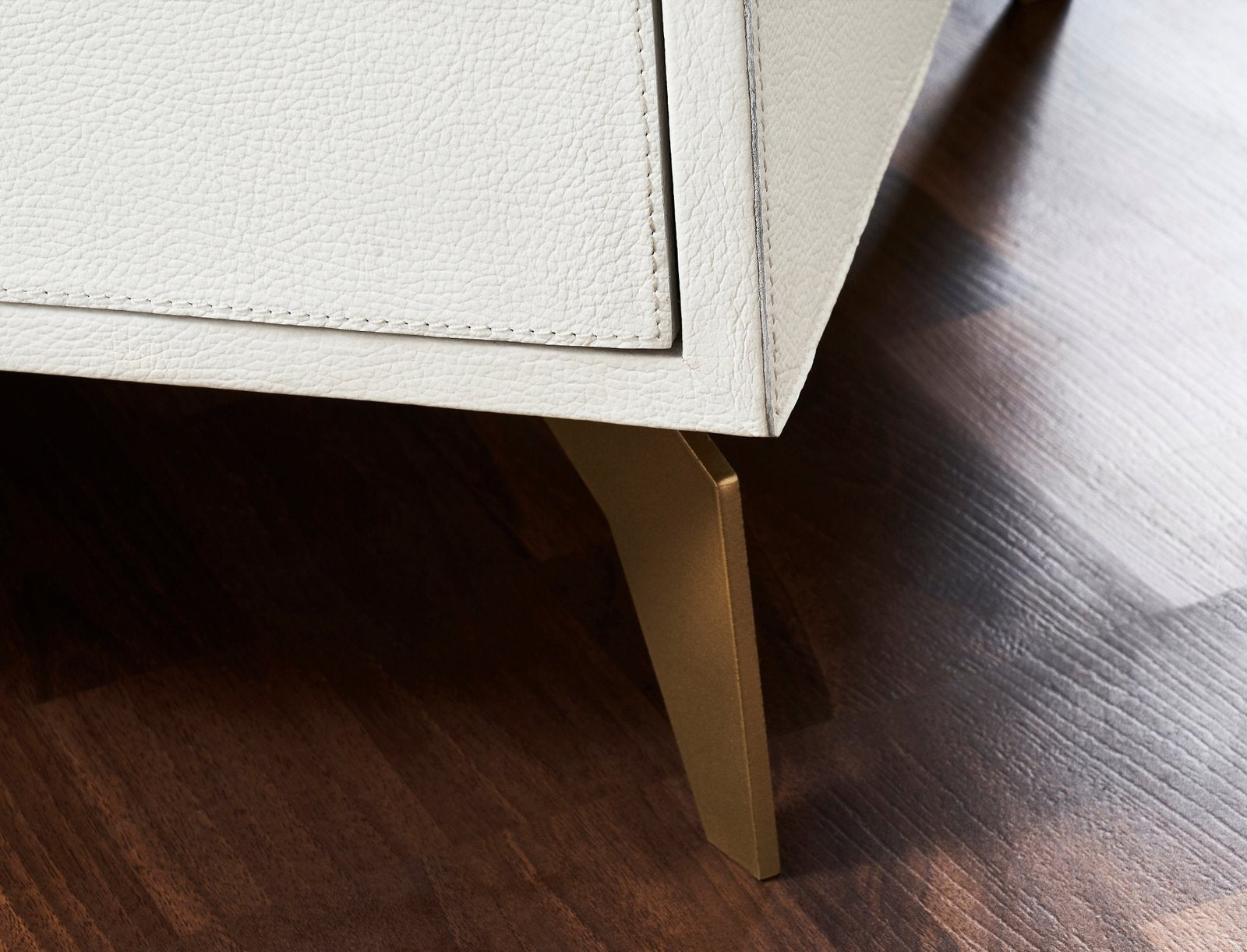 FN-5201-642033_6|Detailed view of the elegant gold-finished leg on the white genuine leather dresser, highlighting premium furniture craftsmanship.