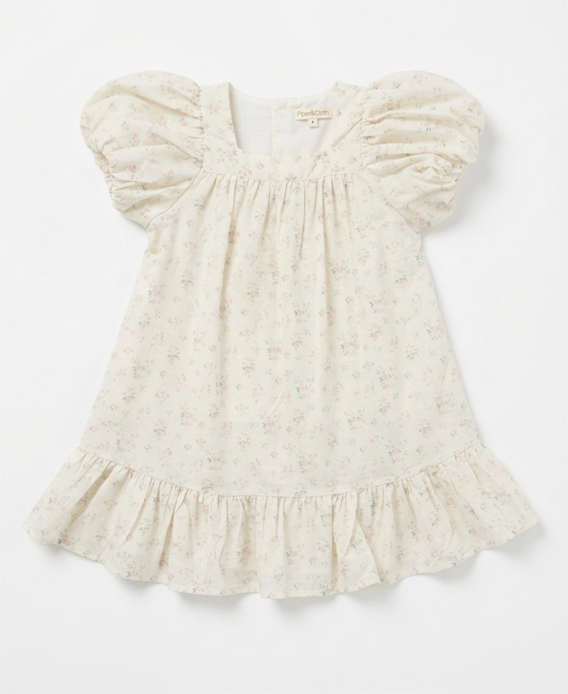 White baby dress with ruffled sleeves on a light gray background