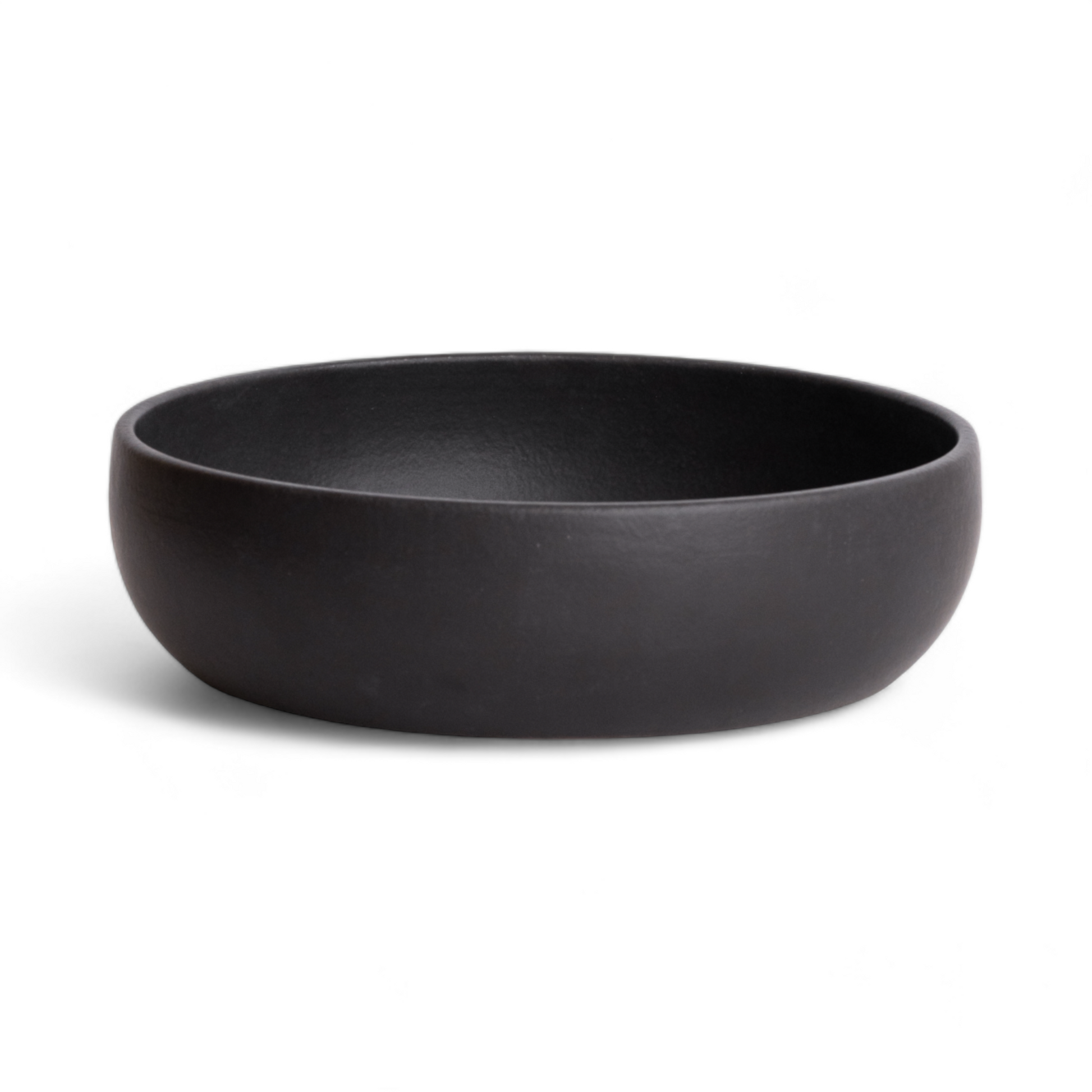 An empty black stoneware shallow serving bowl displayed against a plain white background, highlighting its smooth matte finish and minimalist design.