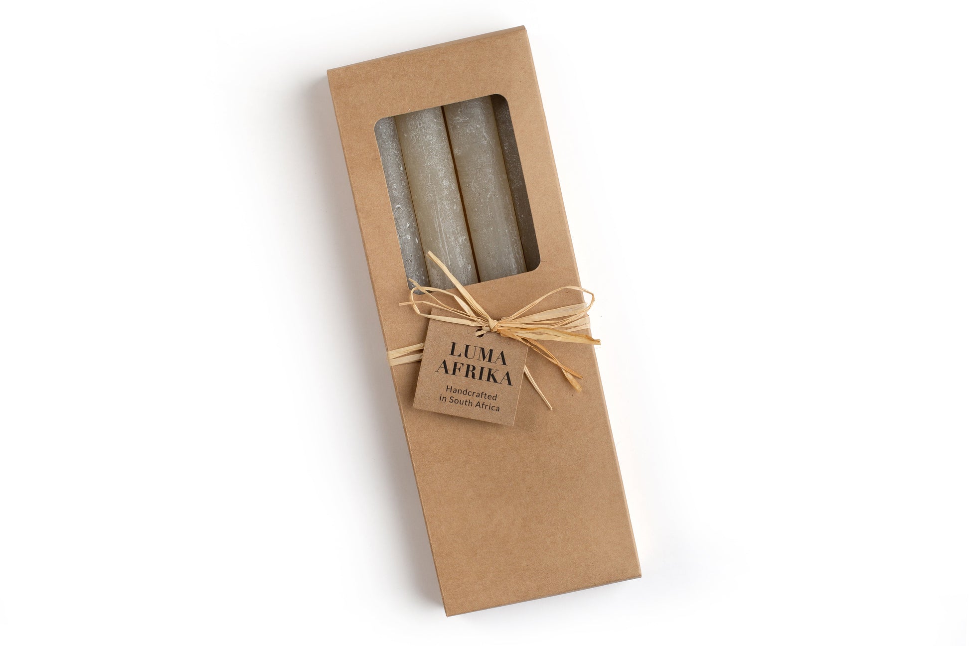 4 white frosted tapers in a kraft bown gift box, ties with raffia and a story card. Luma Afrika. Fair Trade.