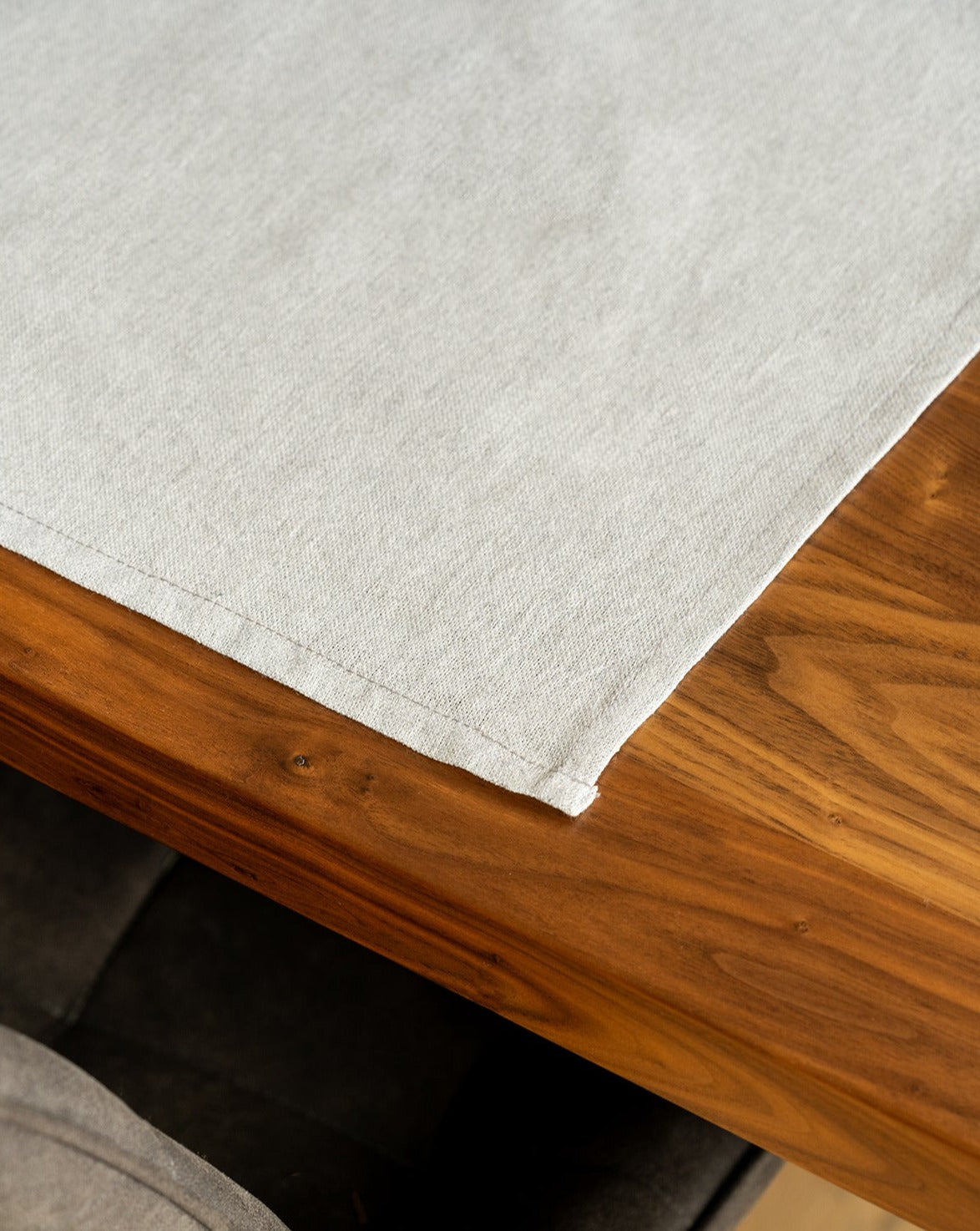 A Light grey cotton placemat is laid out on a wooden table.