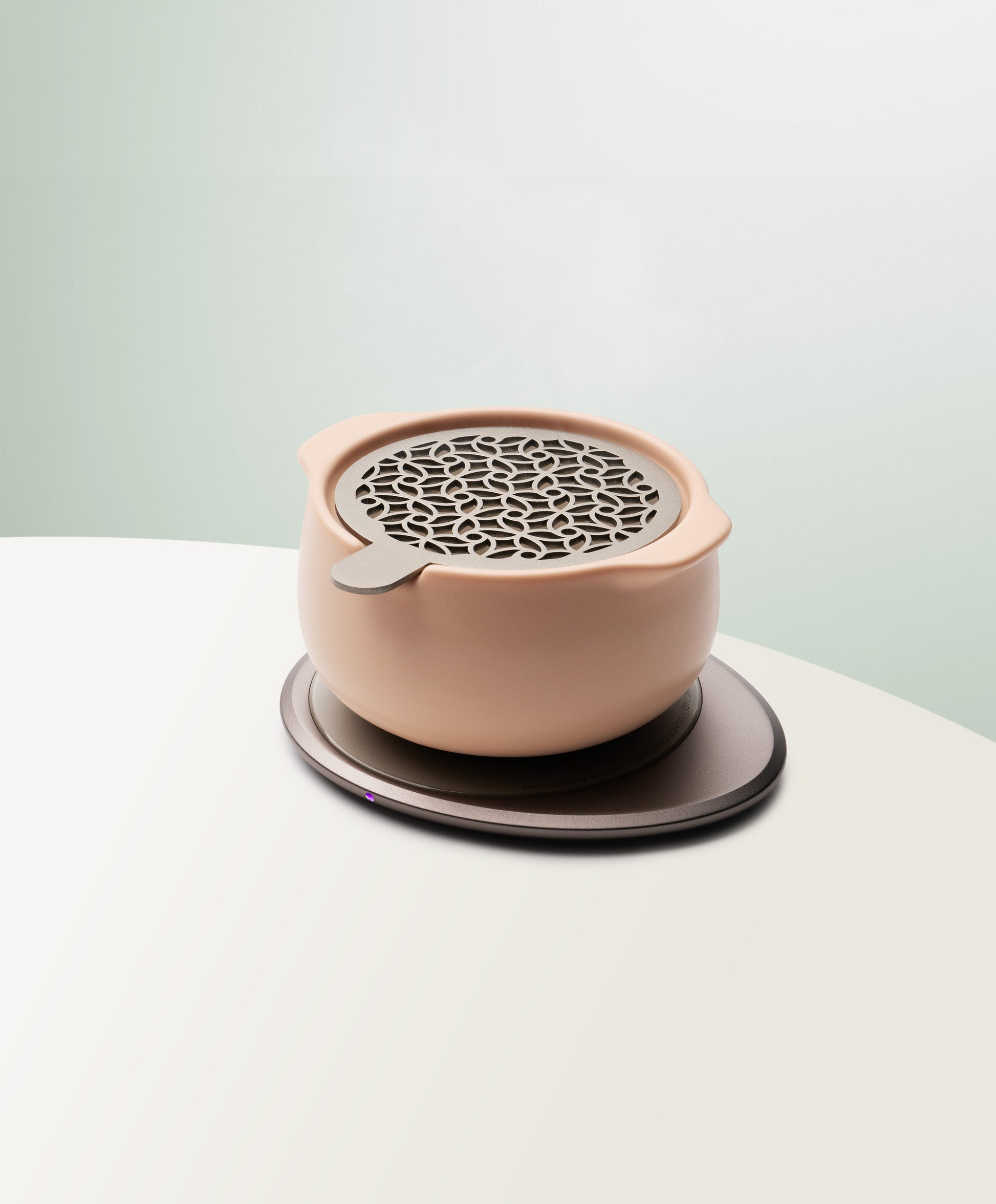 Jun Self-Heating Ceramic Diffuser 5 fl oz / 150 mL with lid in Rosy Apricot angled view on Ohom Pad 3
