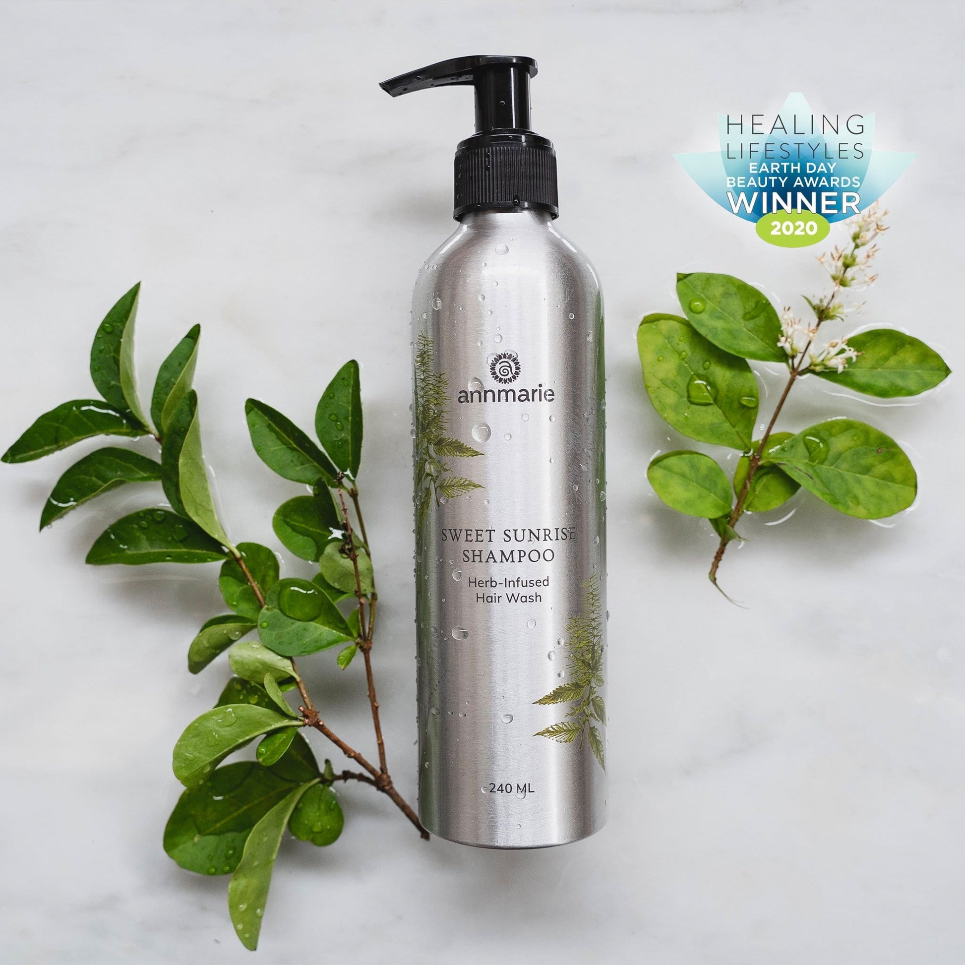 Silver shampoo bottle with green leaves on a light gray background