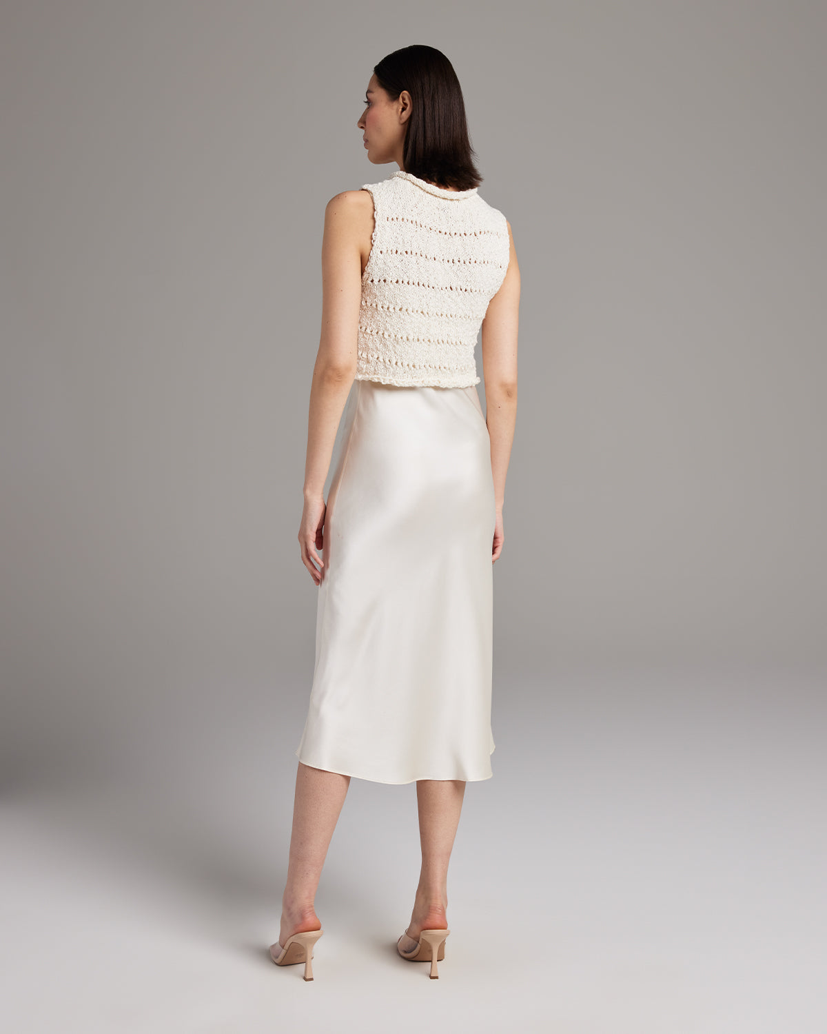 Back view of a model wearing a Flammé Knit Crop Top with a satin skirt