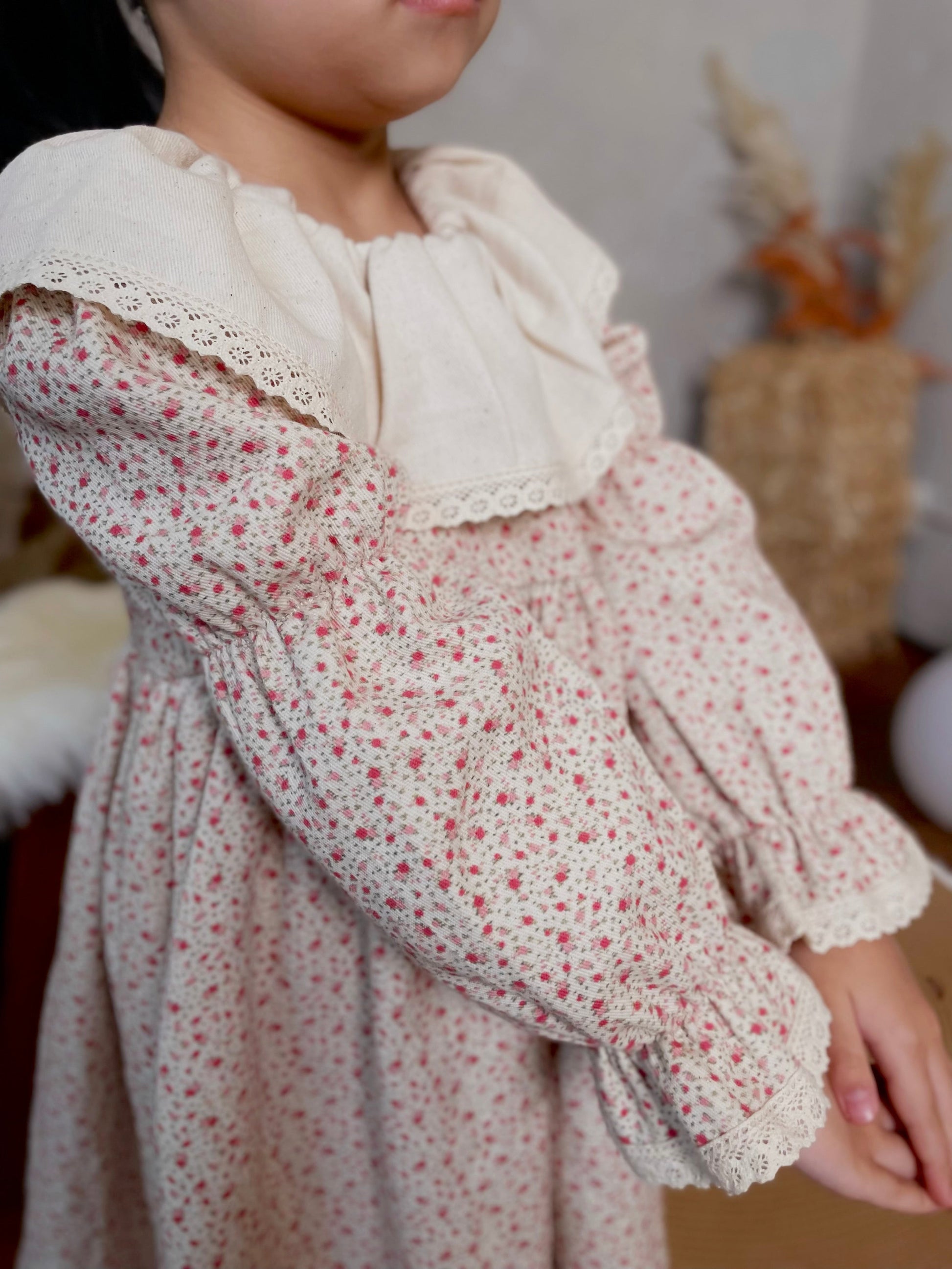Close-up of a person wearing a floral dress with a white lace collar.
