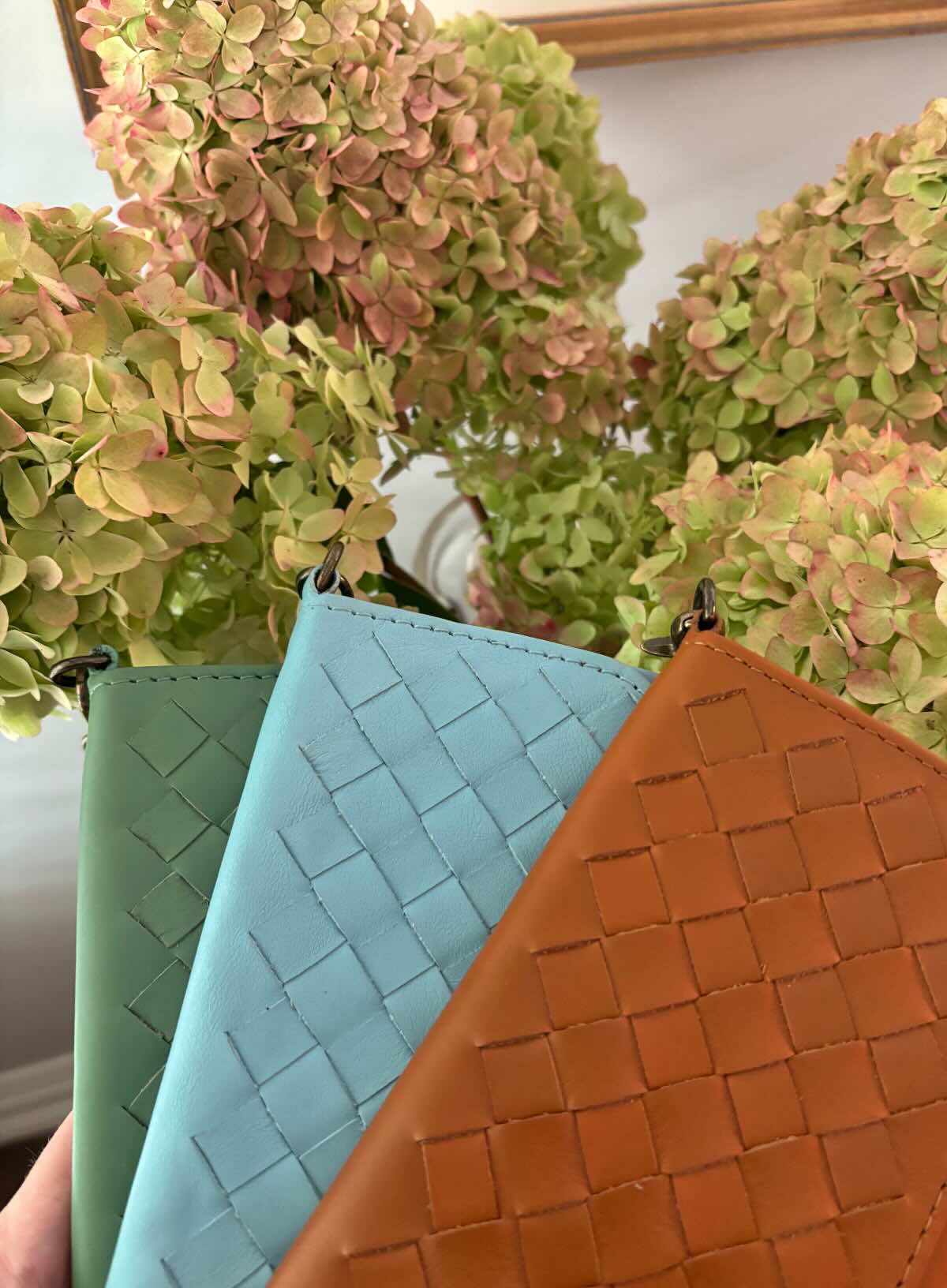 woven wristlets in different colors in front of flowers.