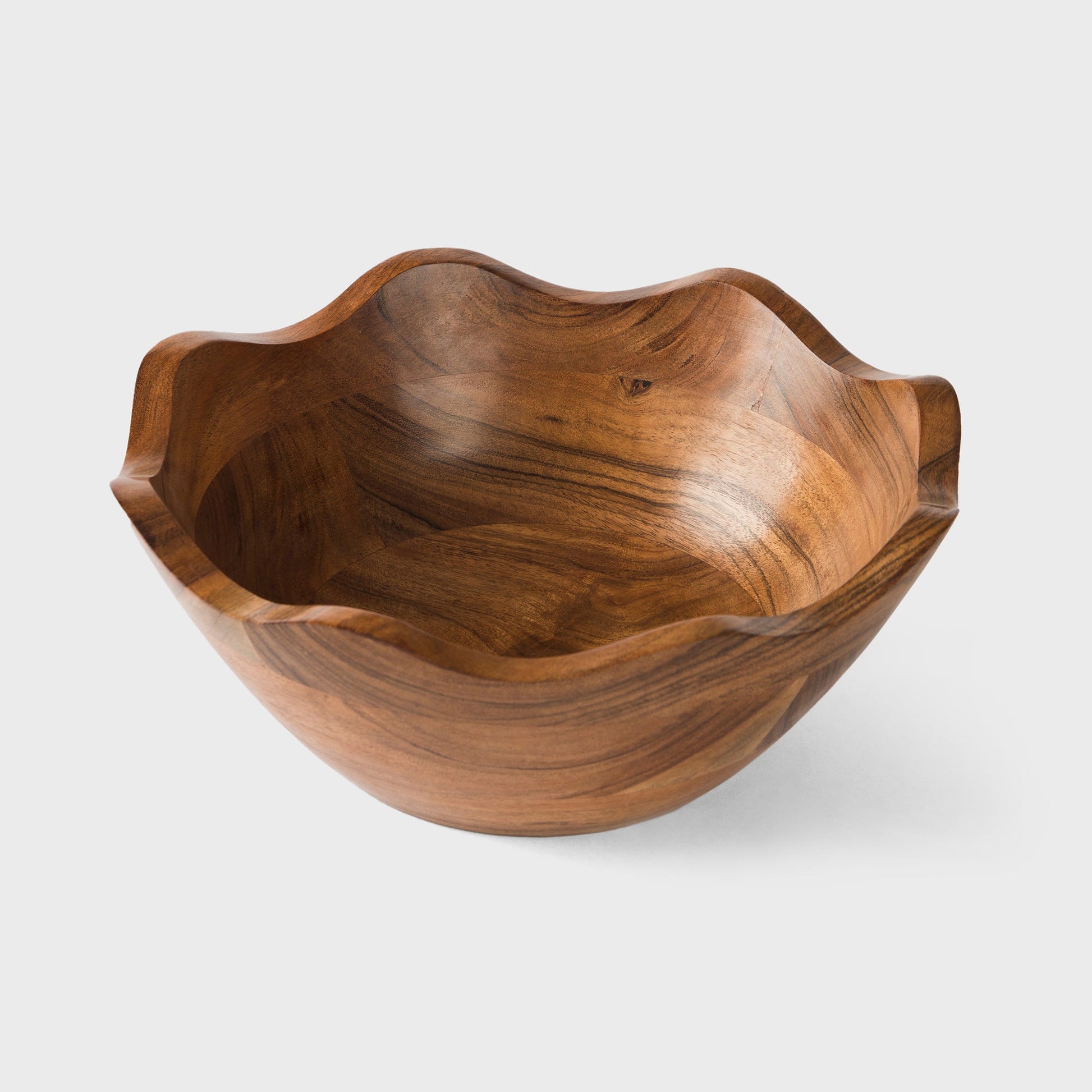 Handcrafted wavy edge wooden bowl used as a rustic table centerpiece.