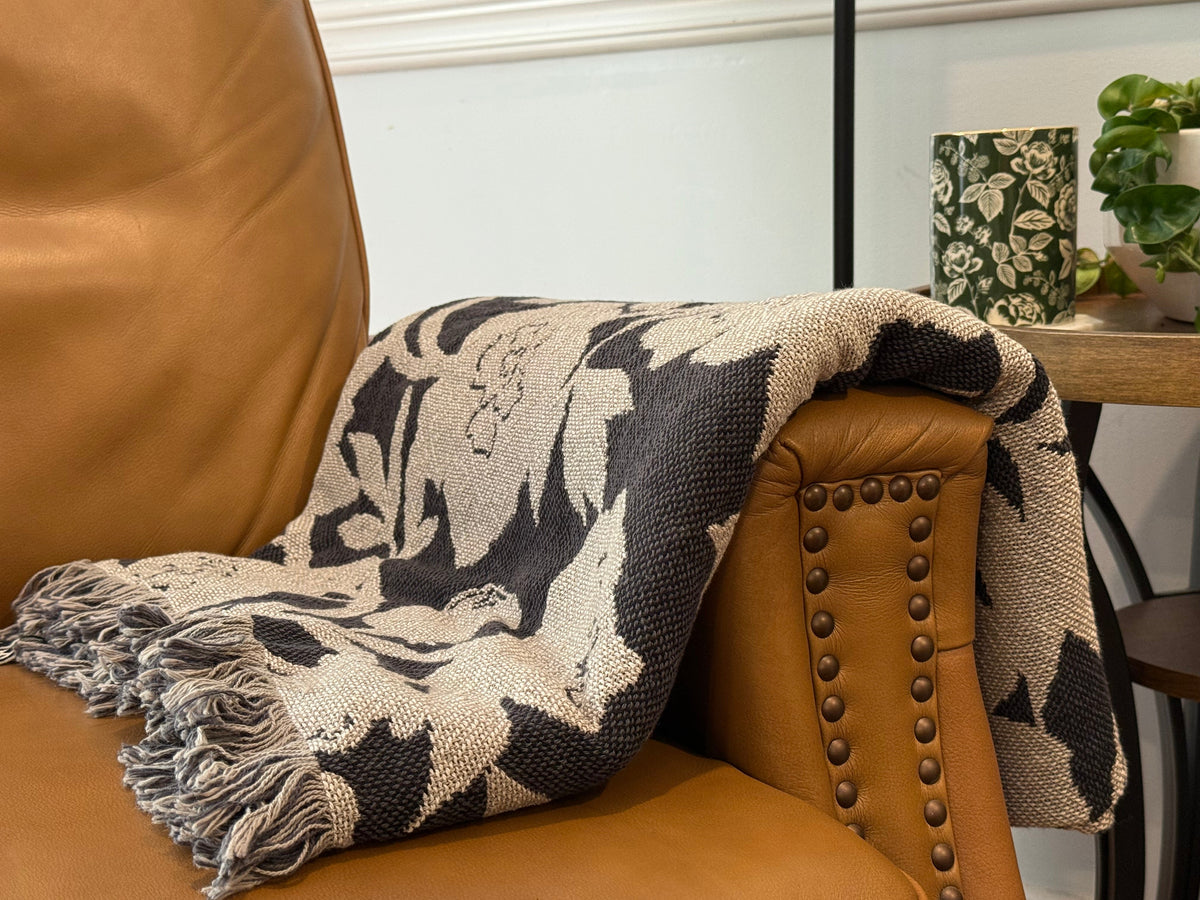 Patterned throw blanket draped over a brown armchair with a blurred indoor setting.