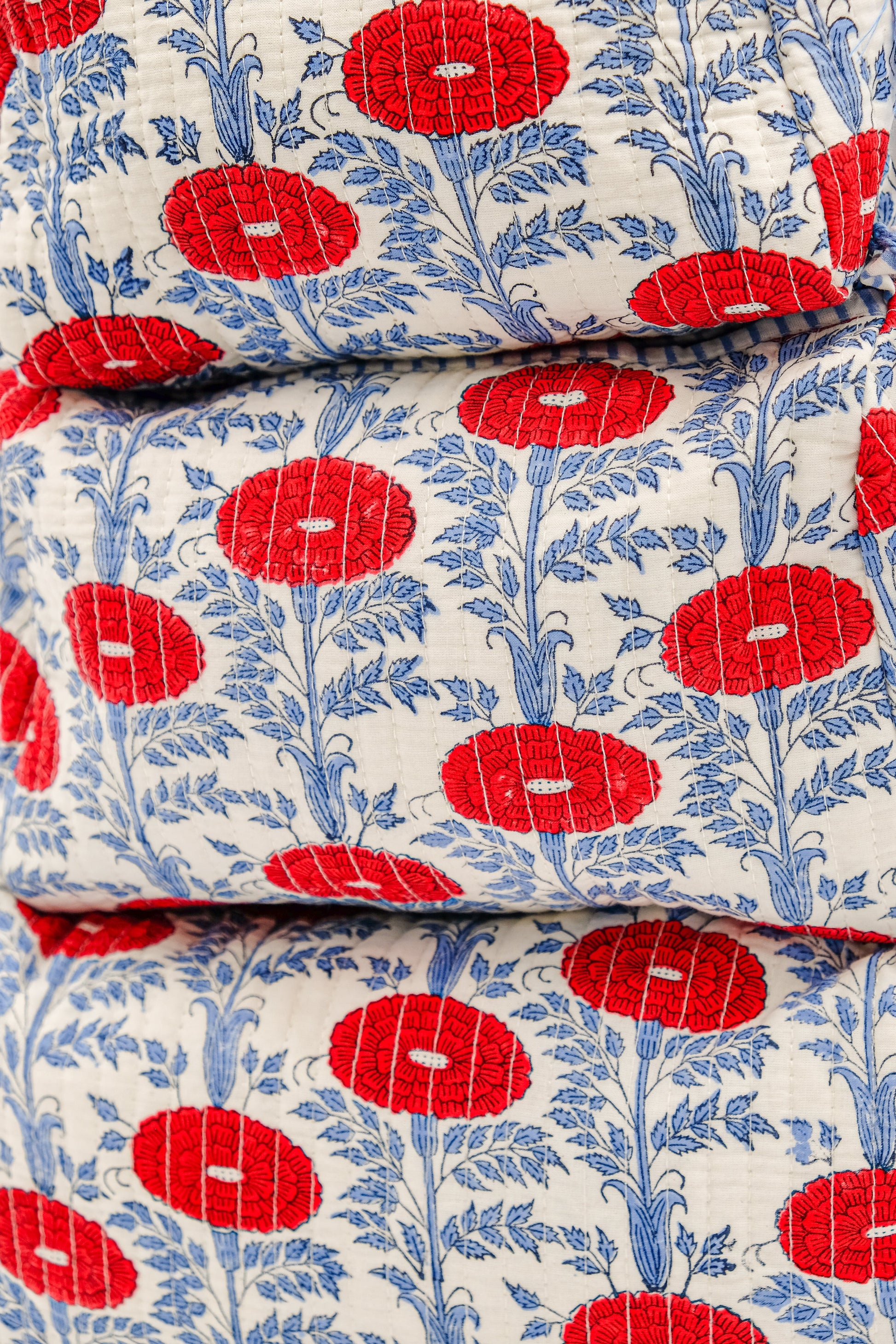 Vibrant red floral toiletry bag fabric stack with blue foliage pattern