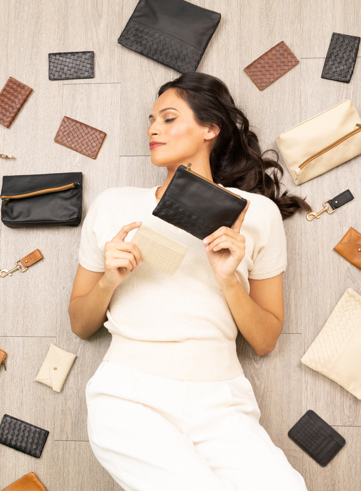 model lying down surrounded by leather accessories.